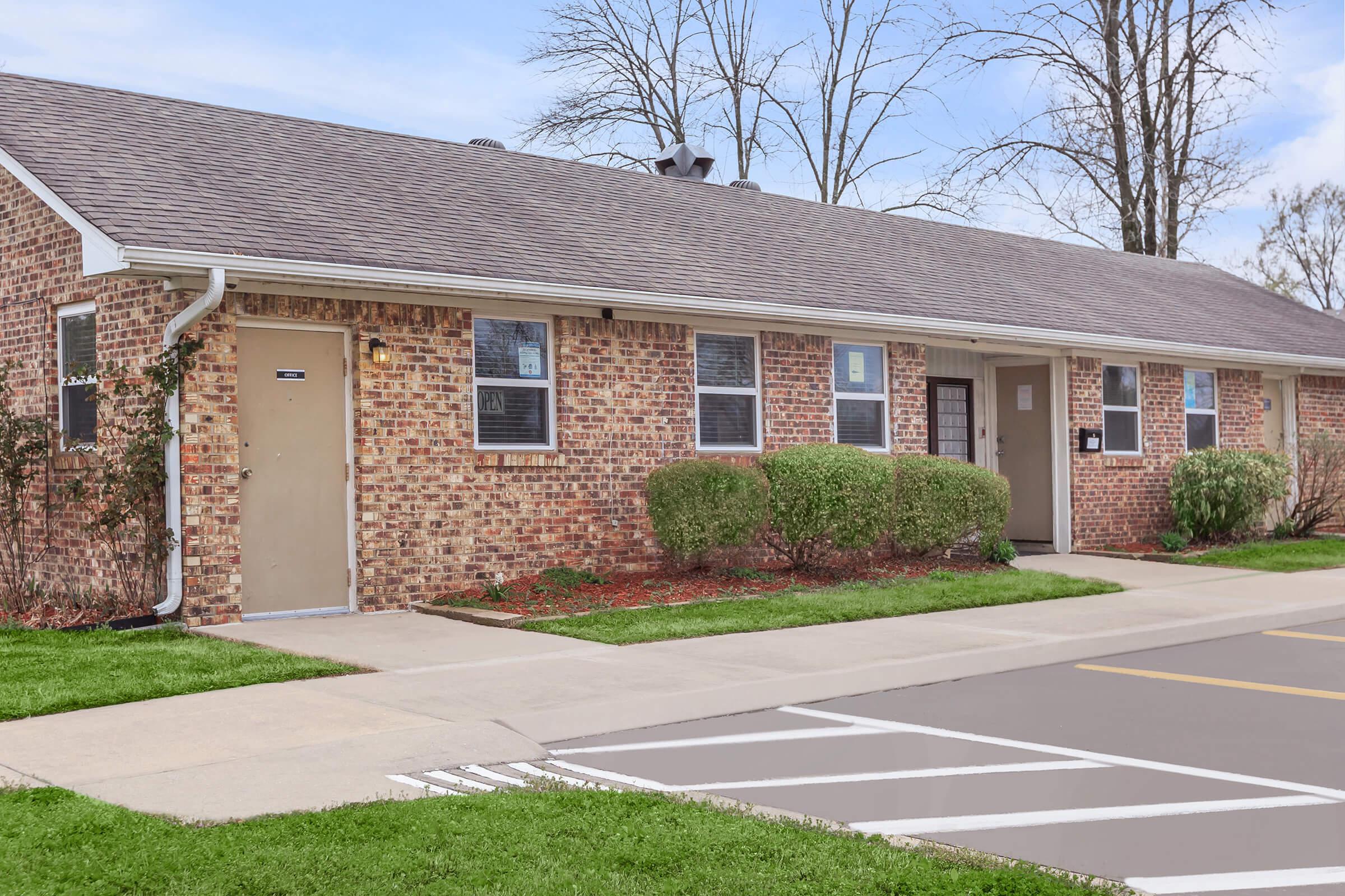 a large brick building with grass in front of a house