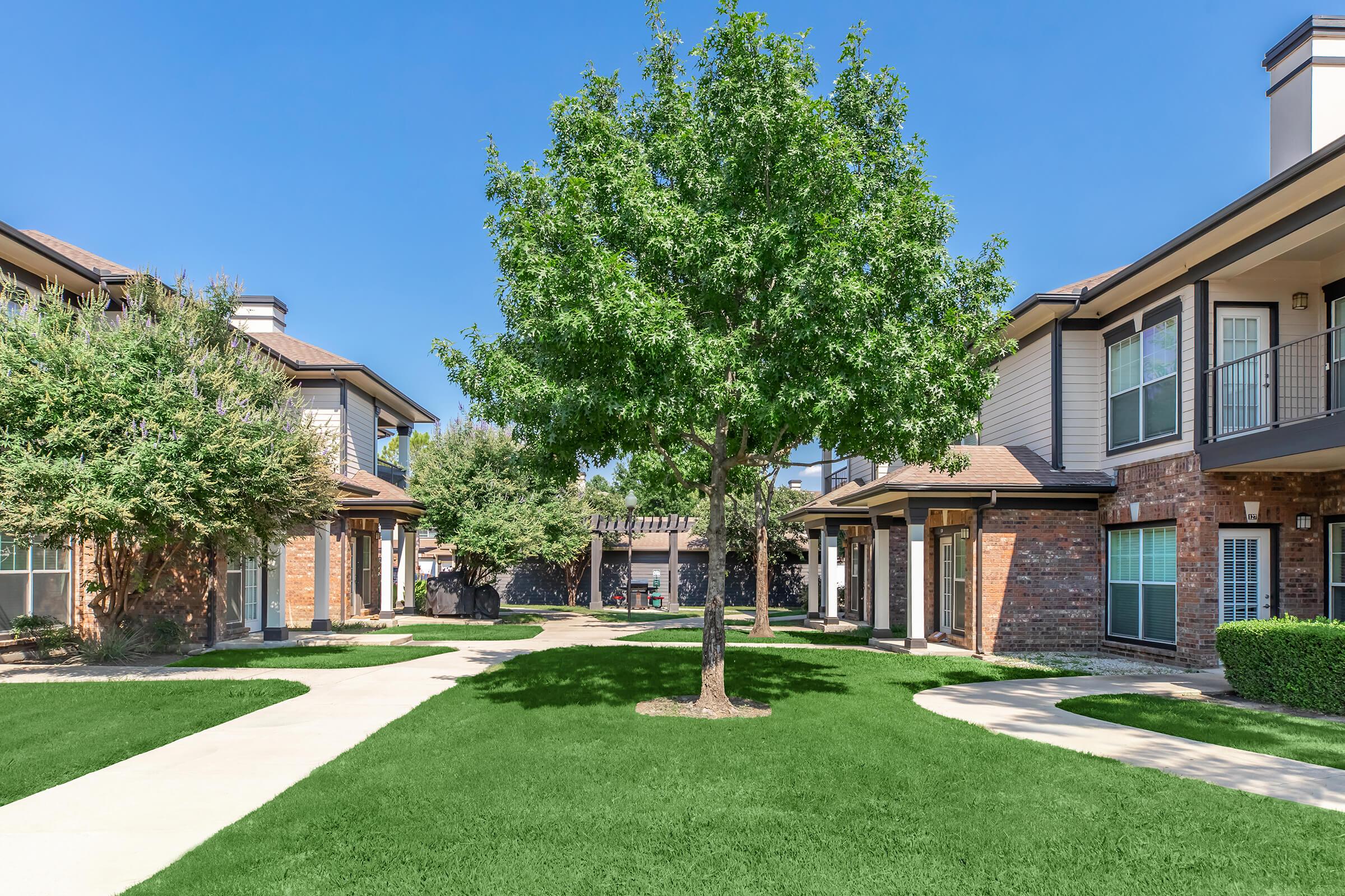 a house with a lawn in front of a brick building