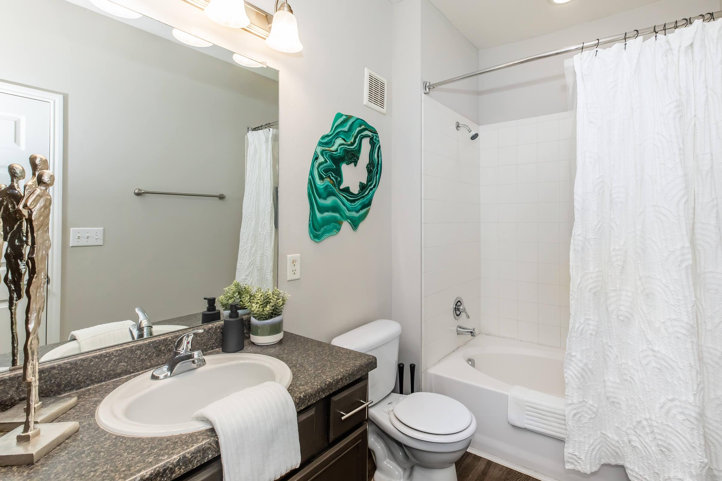 a room with a sink mirror and shower curtain