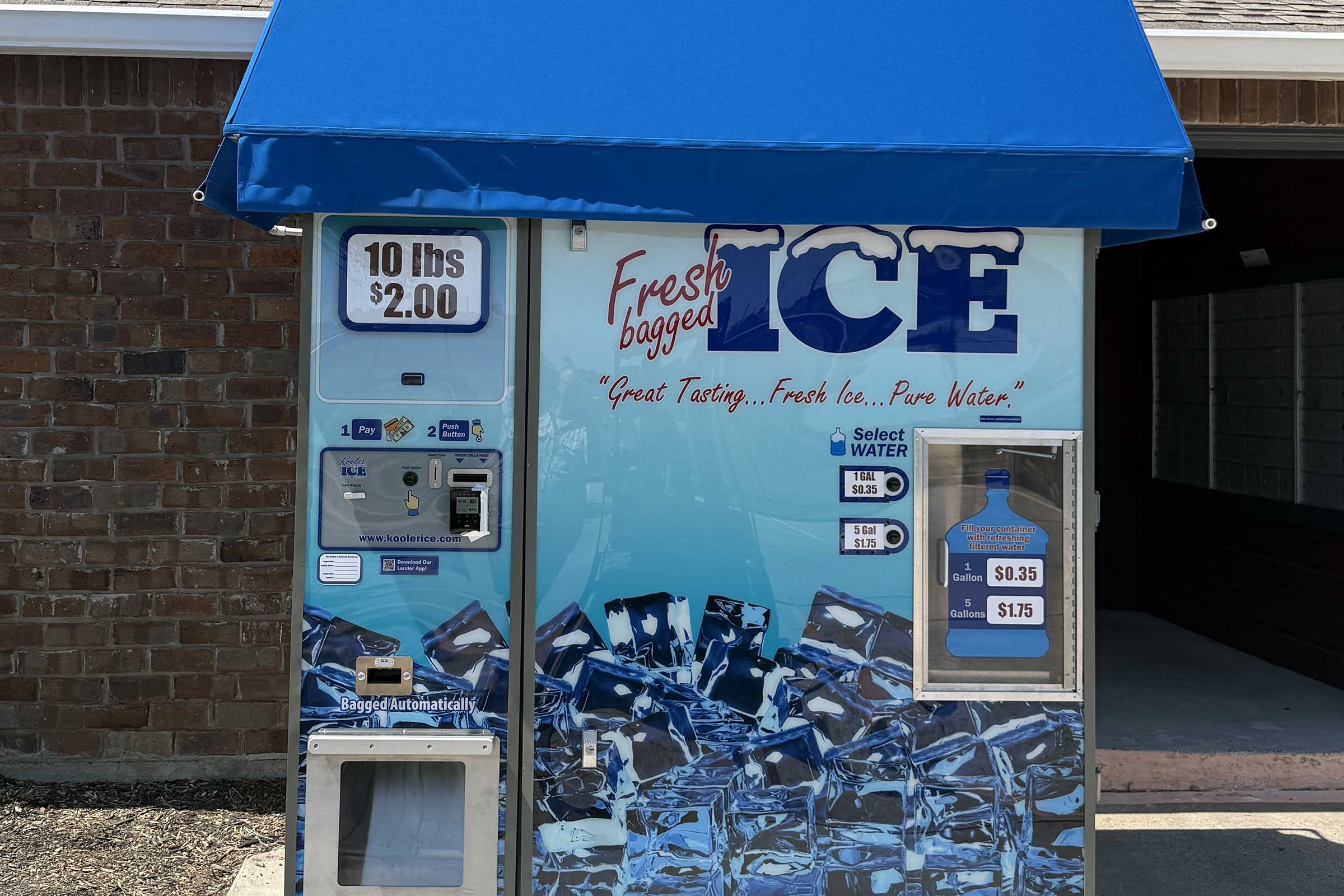 Vending machine for fresh bagged ice with a blue roof and promotional text. Price for 10 lbs of ice is $2.00. Additional pricing includes $0.35 for water and $1.75 for other selections. The front features images of ice and a water bottle.