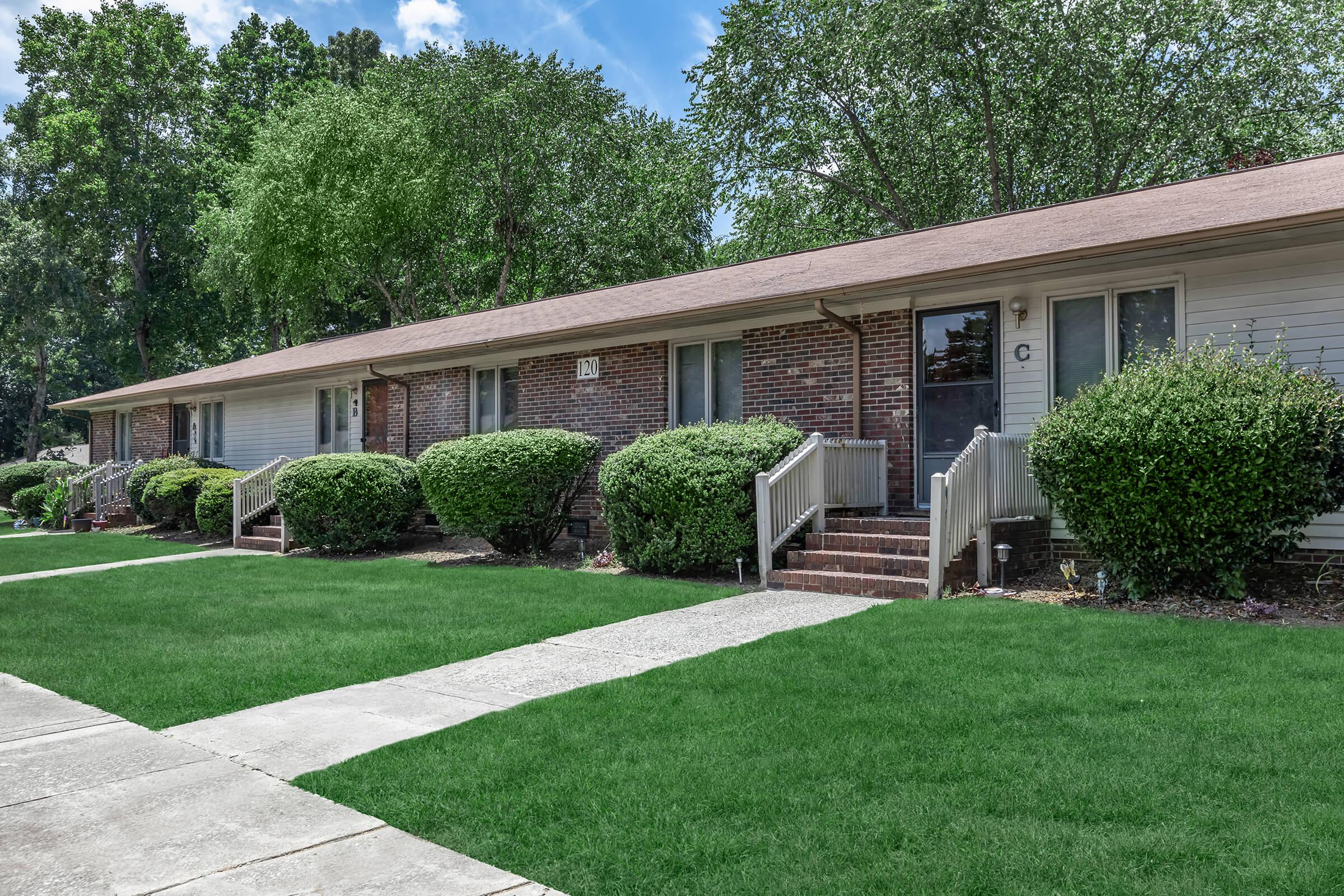 a house with a lawn in front of a brick building