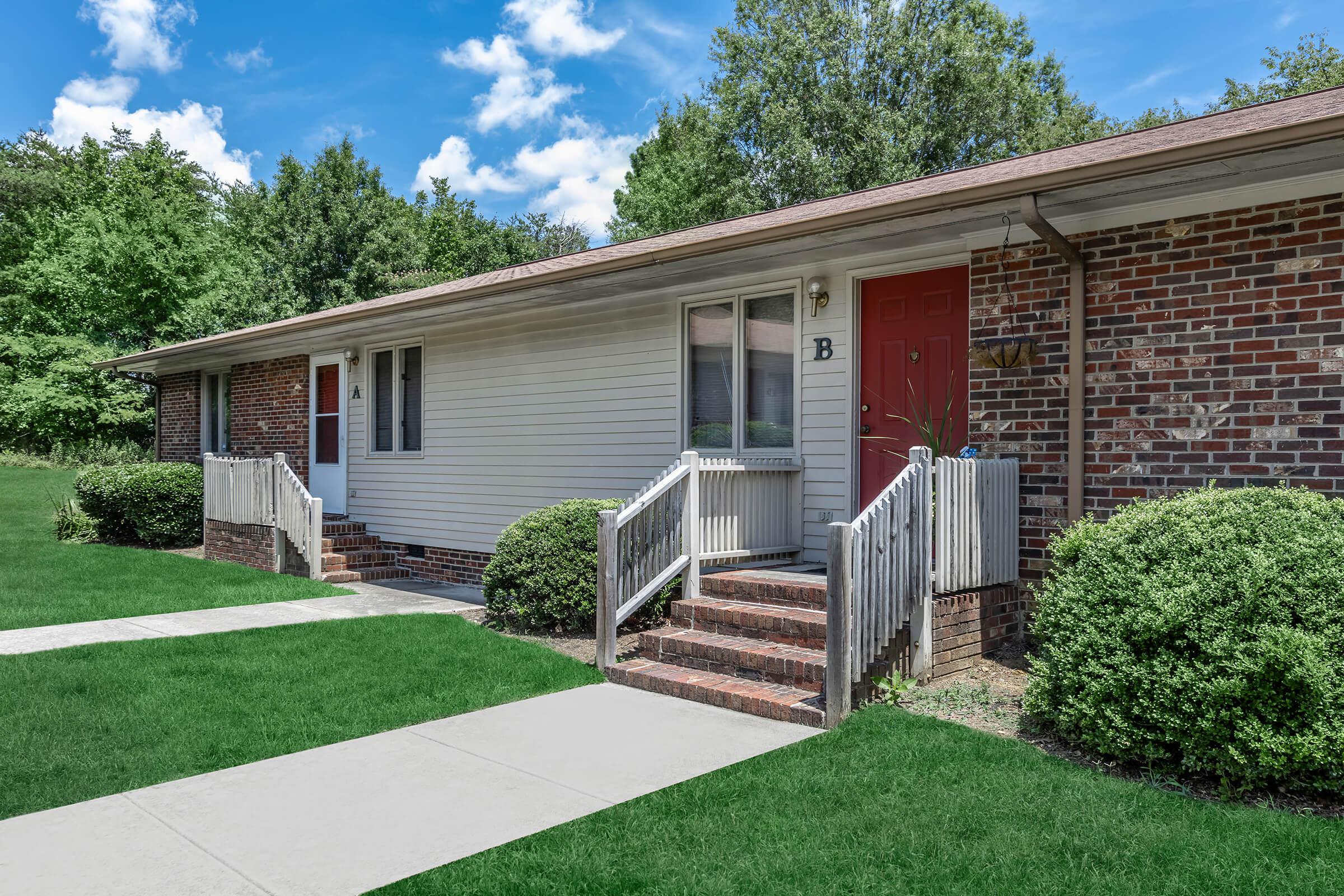 a house with a lawn in front of a brick building