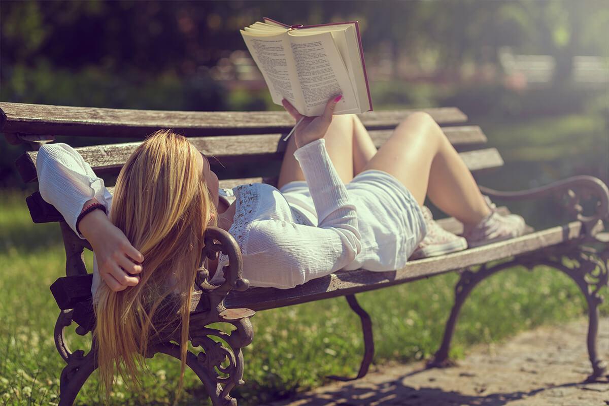 a person sitting on a bench reading a book