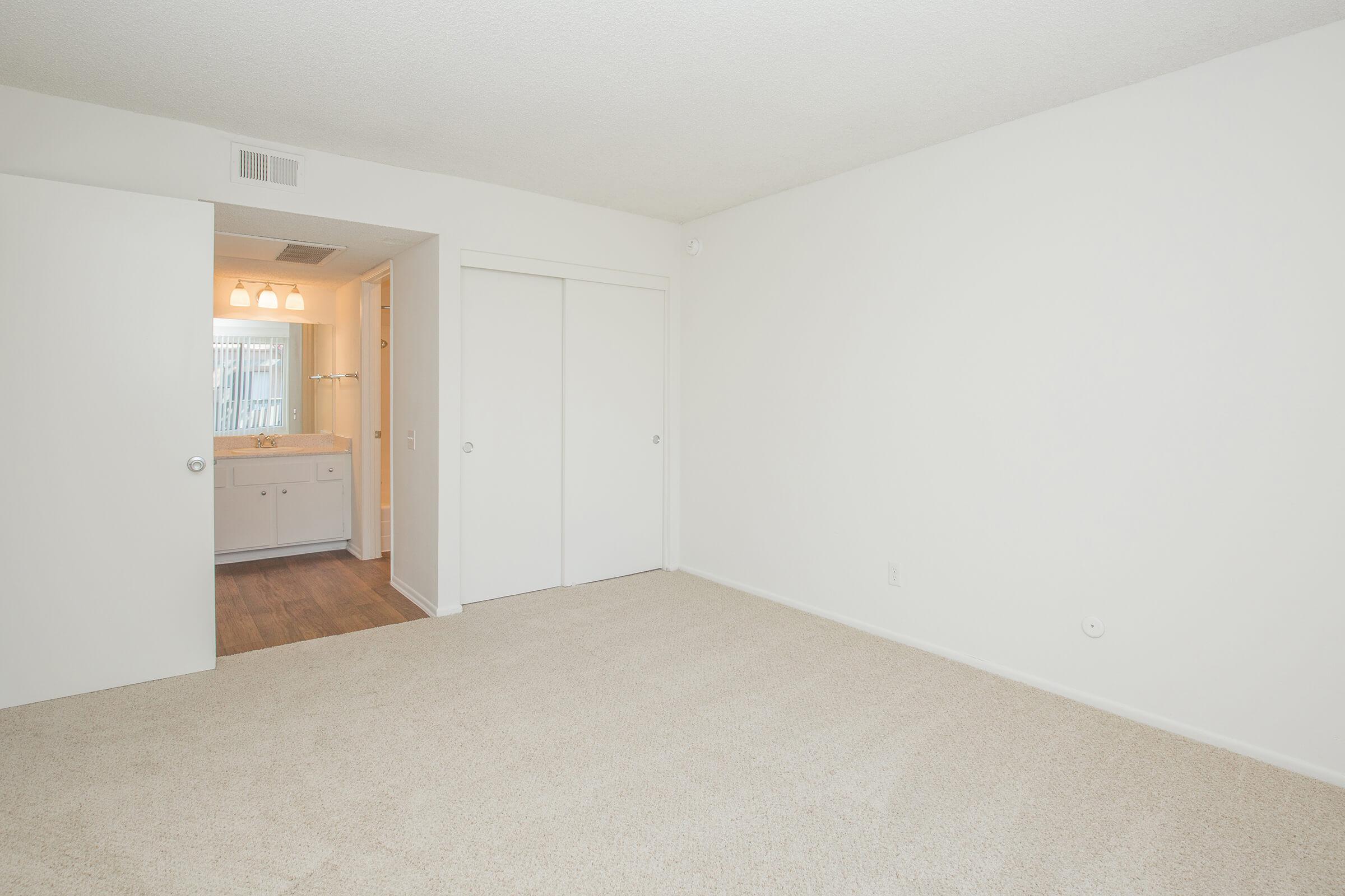 Carpeted bedroom with open bathroom door