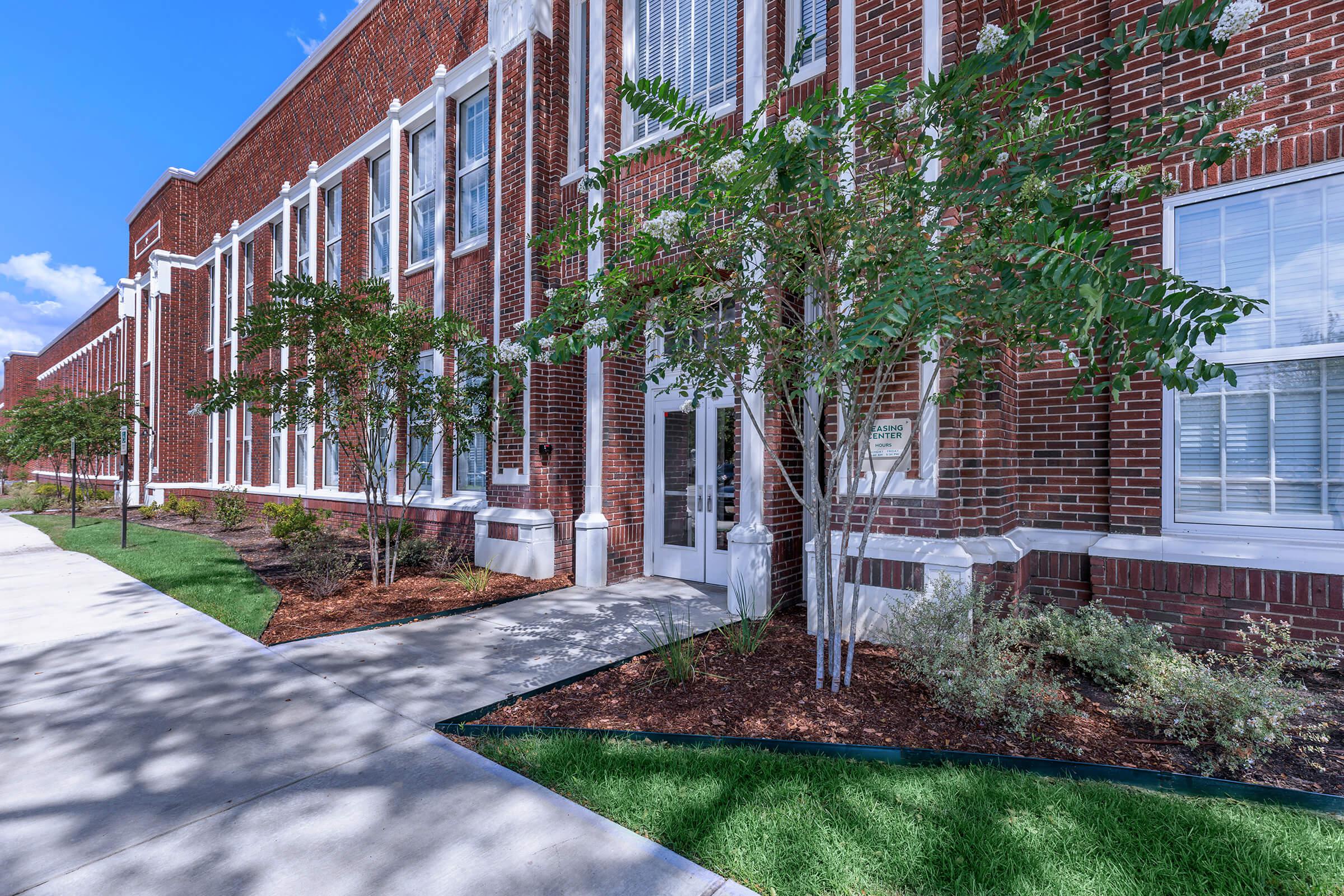 a large brick building with grass and trees