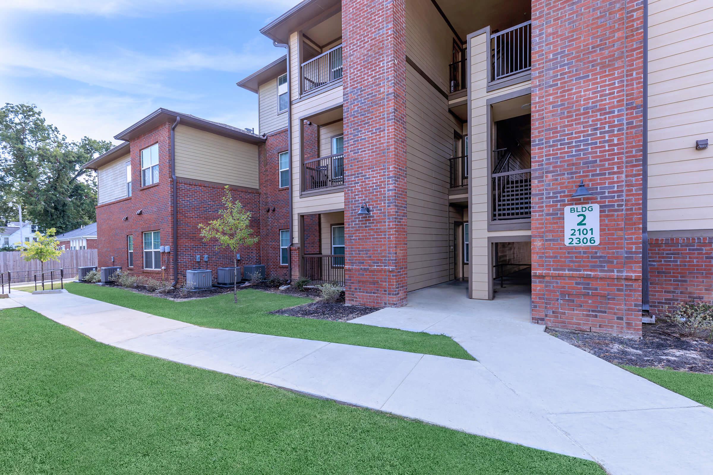 a house with a lawn in front of a brick building