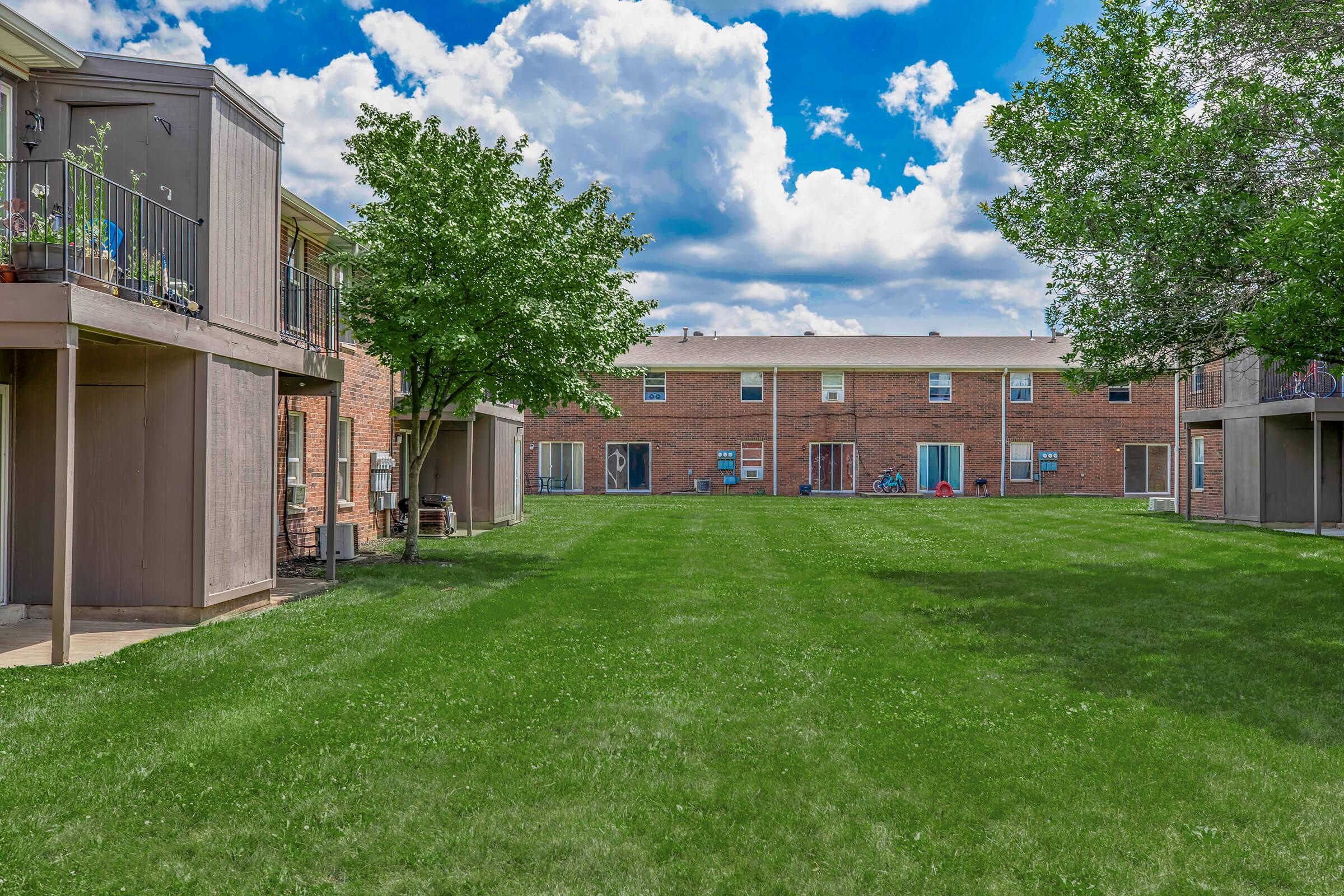 a large brick building with grass in front of a house