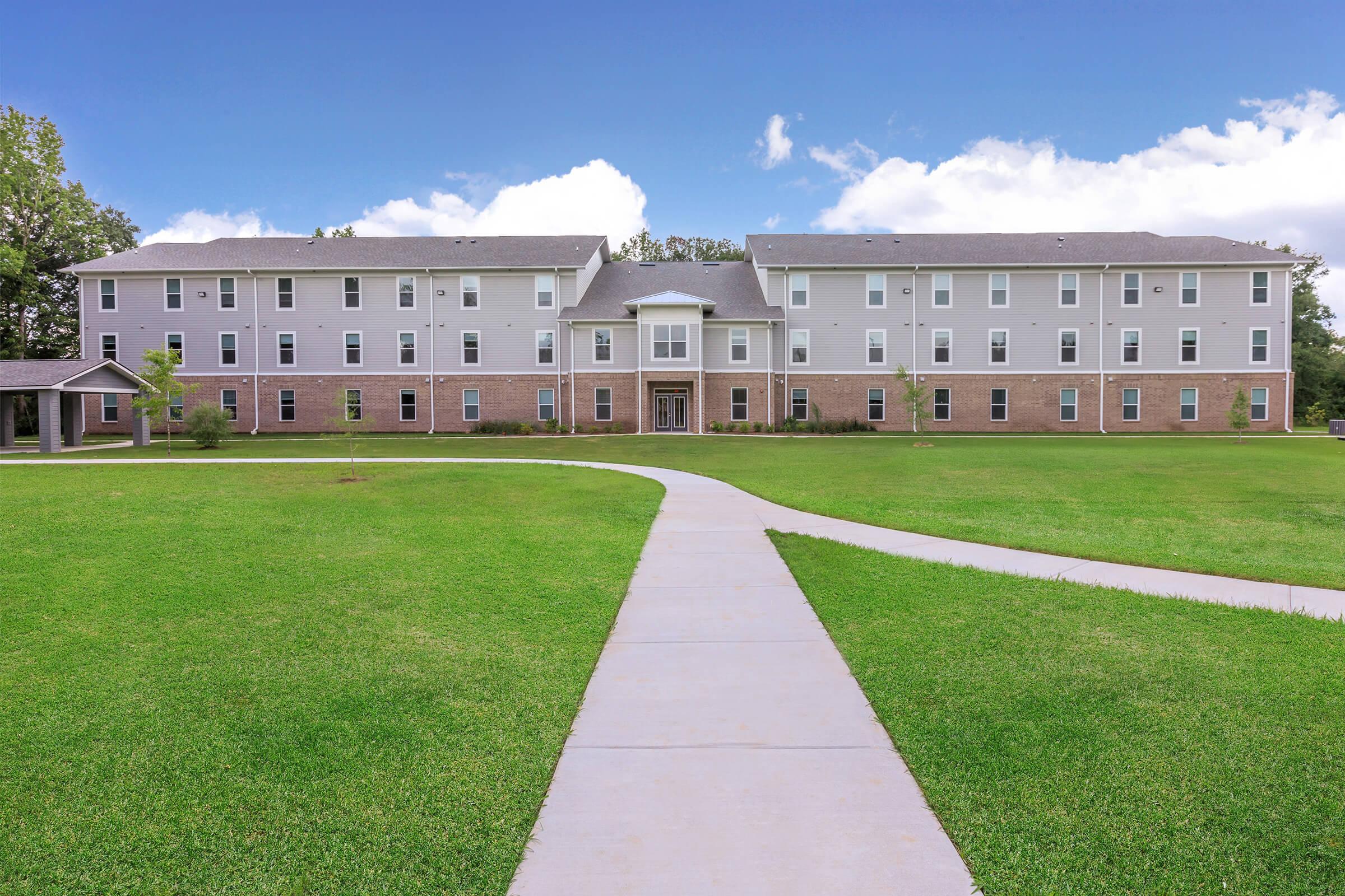 a large brick building with green grass