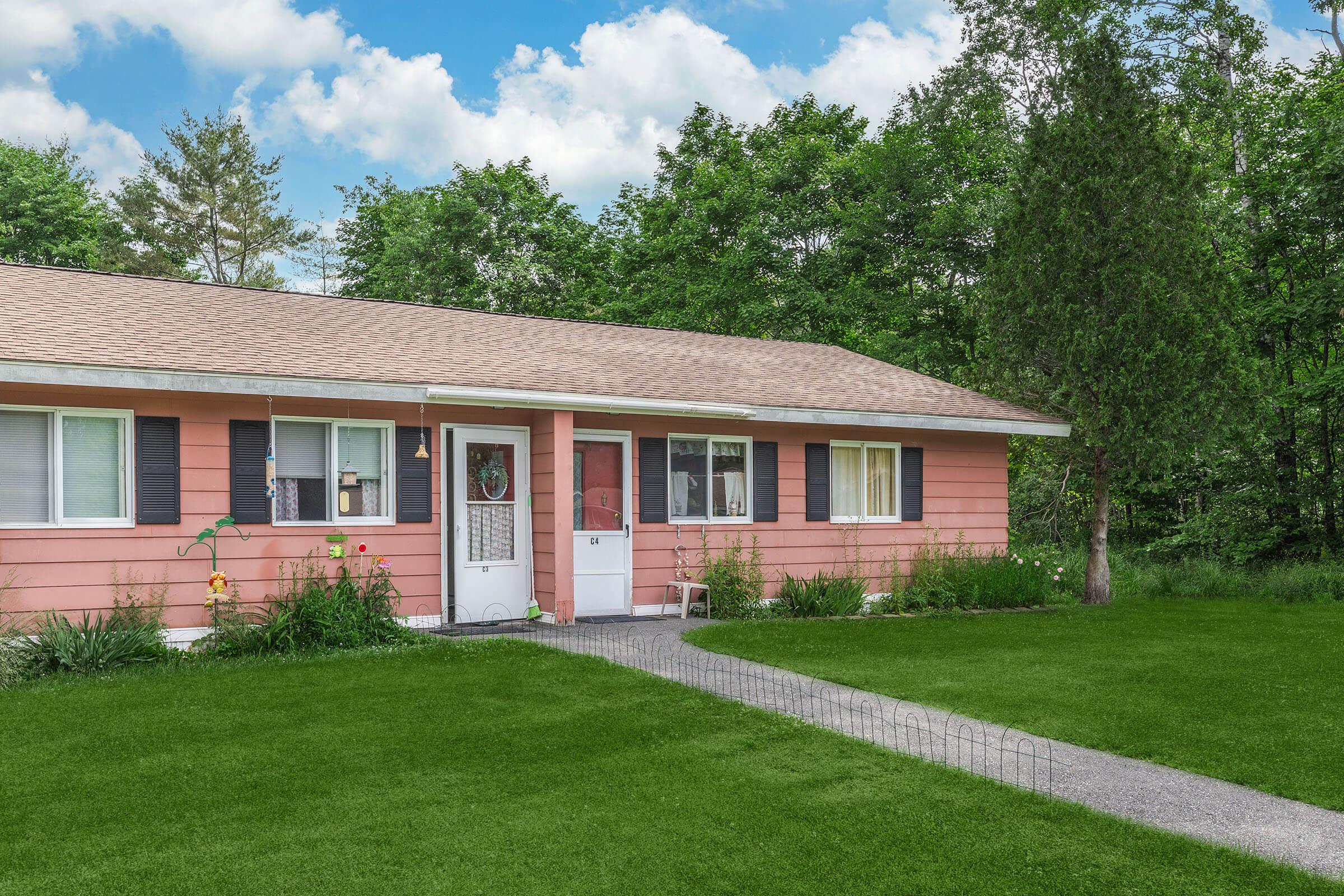 a house with a lawn in front of a brick building