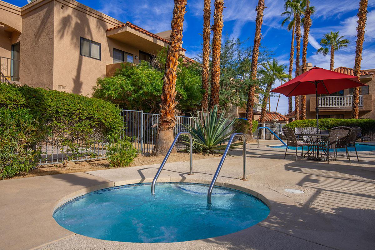 a pool next to a palm tree in front of a building