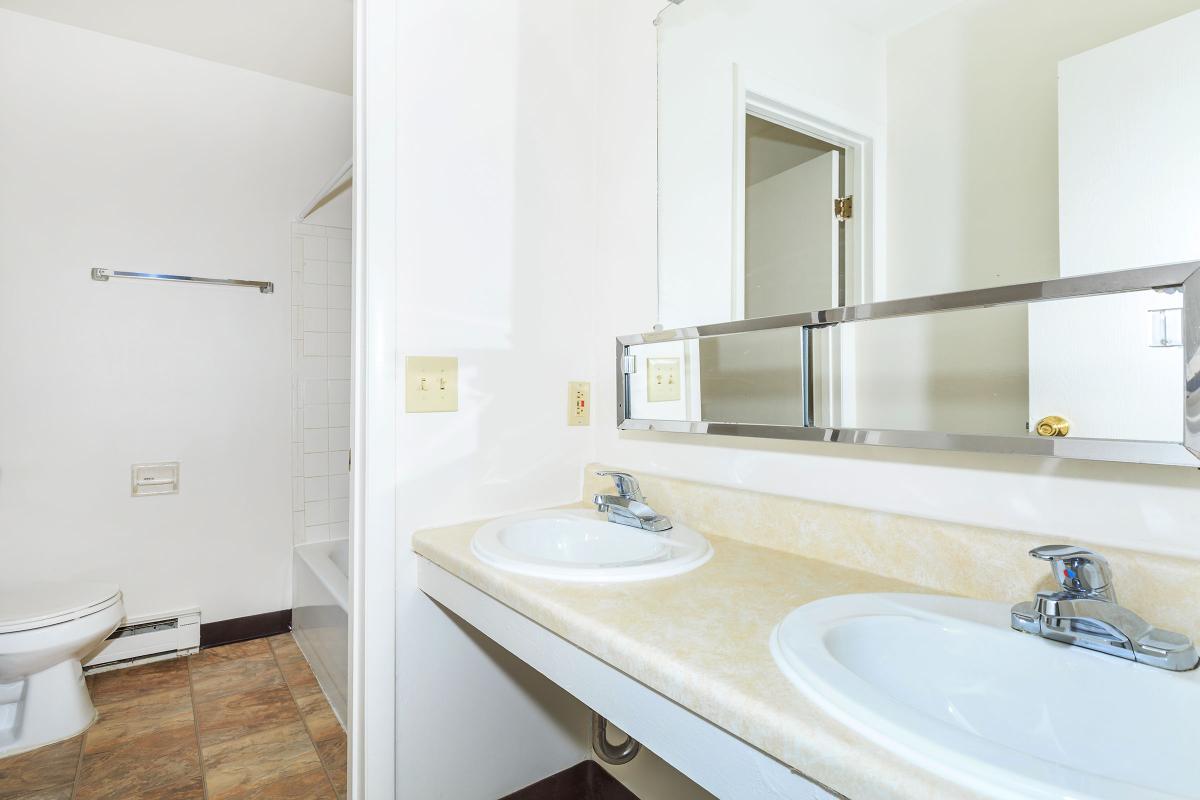 a white sink sitting under a mirror