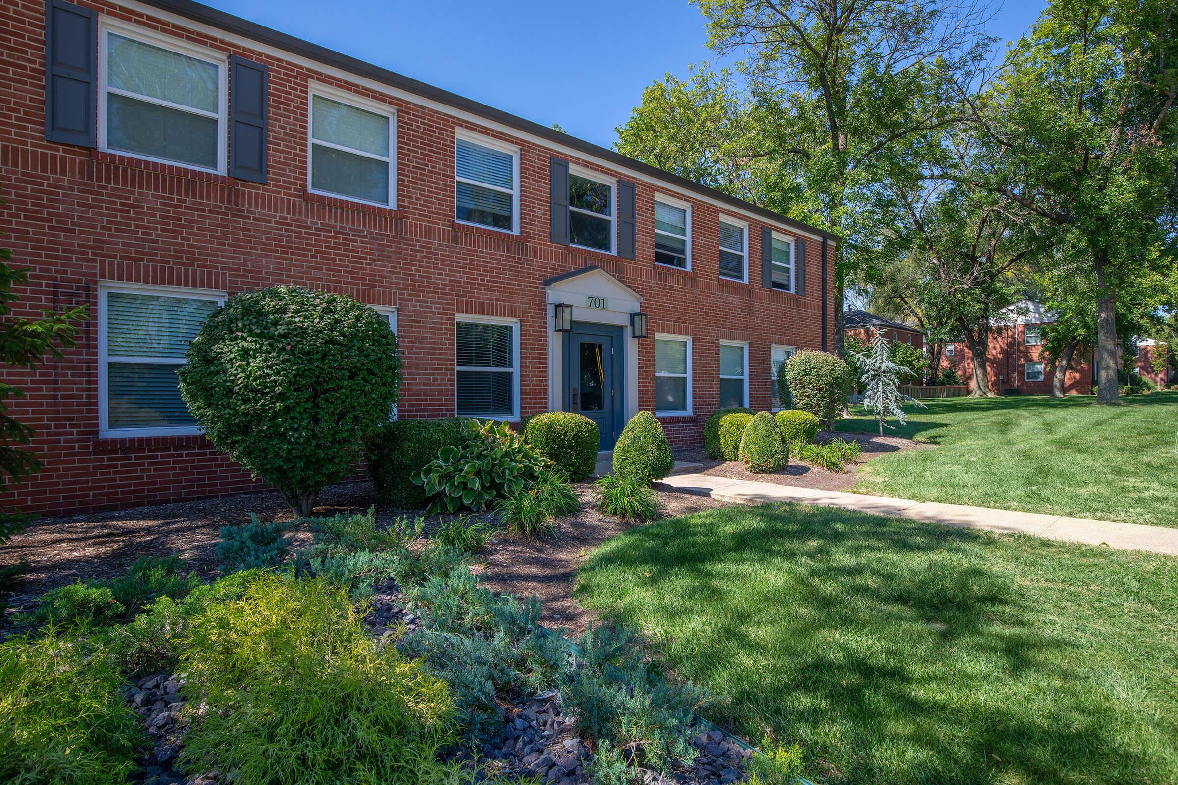 a large brick building with grass in front of a house