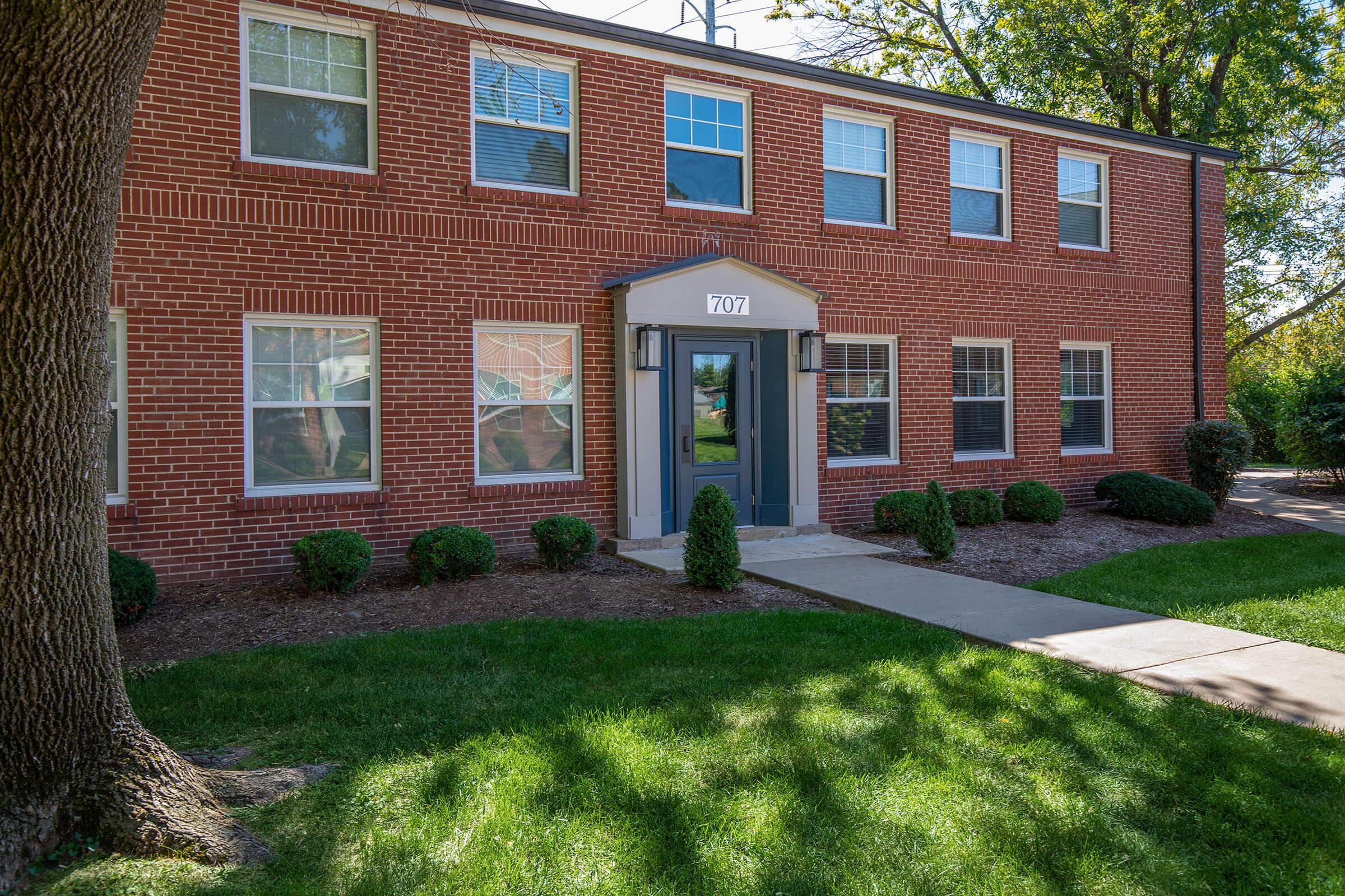 a large brick building with grass in front of a house