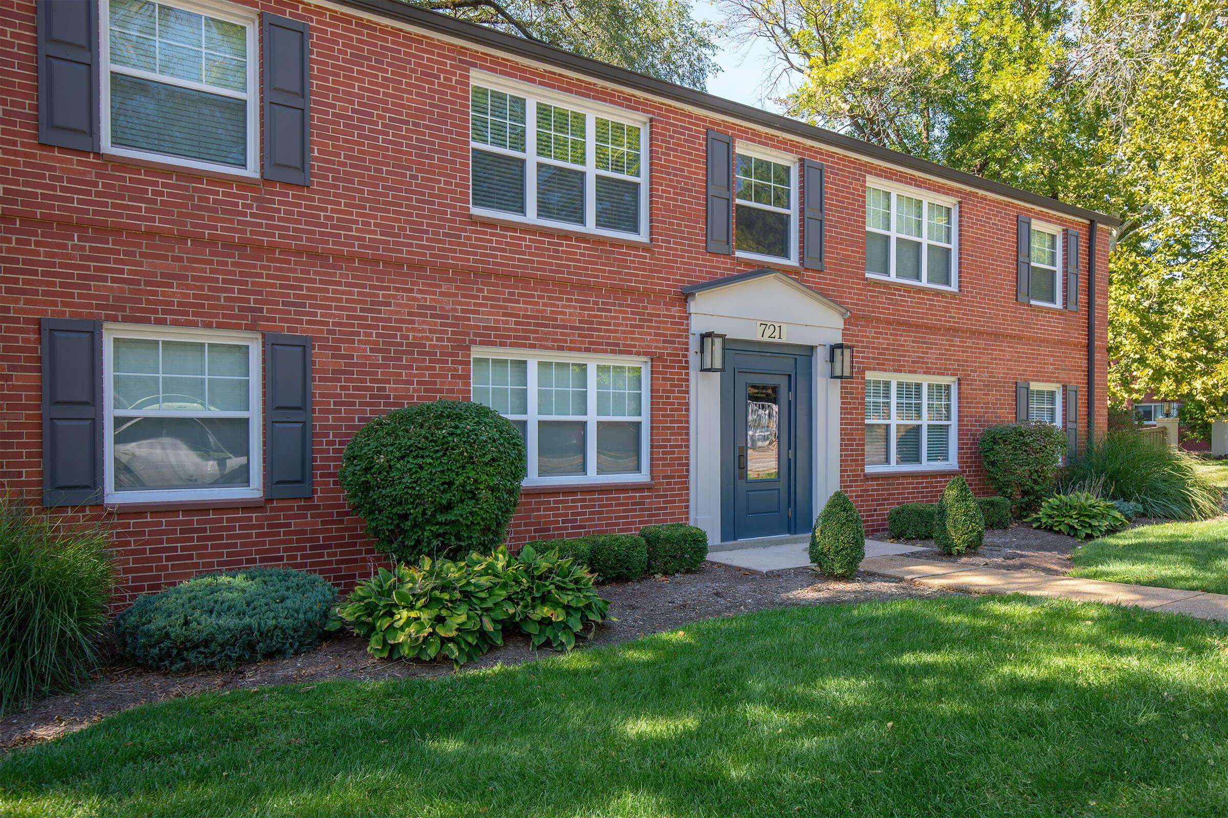 a large brick building with grass in front of a house