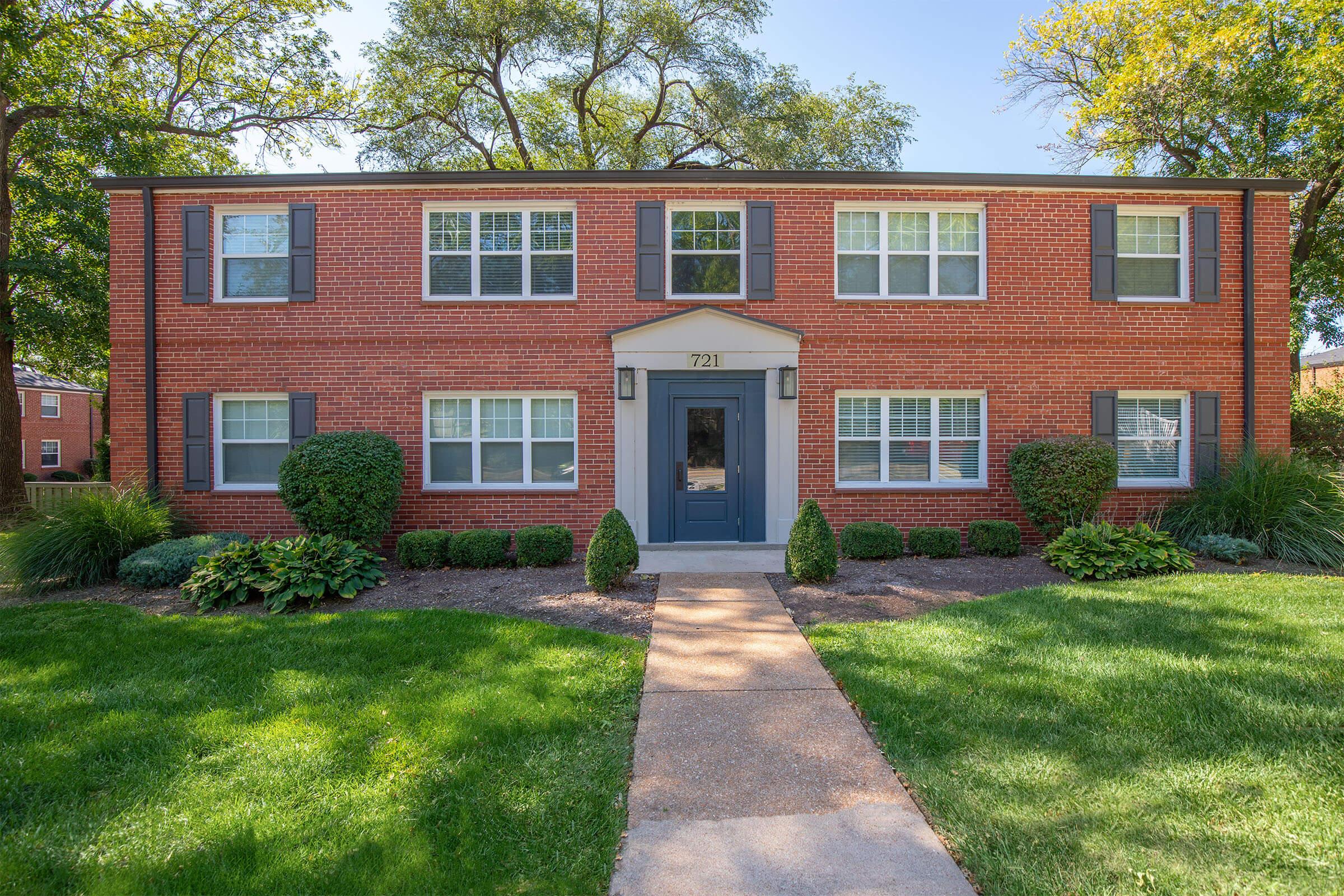 a large brick building with grass in front of a house