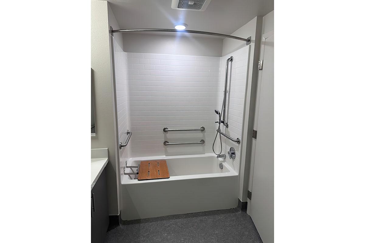 A spacious bathroom featuring a tub with a showerhead and a curved shower rod.