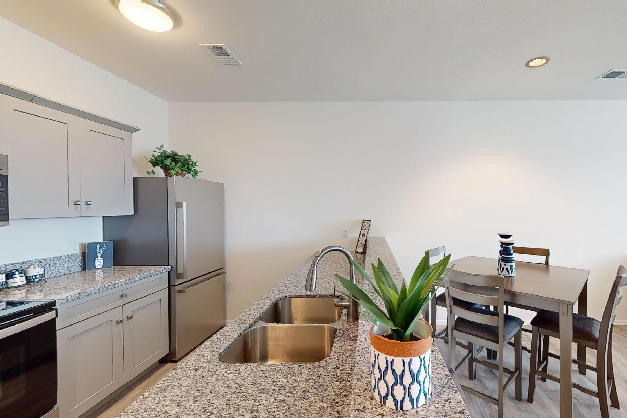 a room filled with furniture and vase of flowers on a kitchen counter