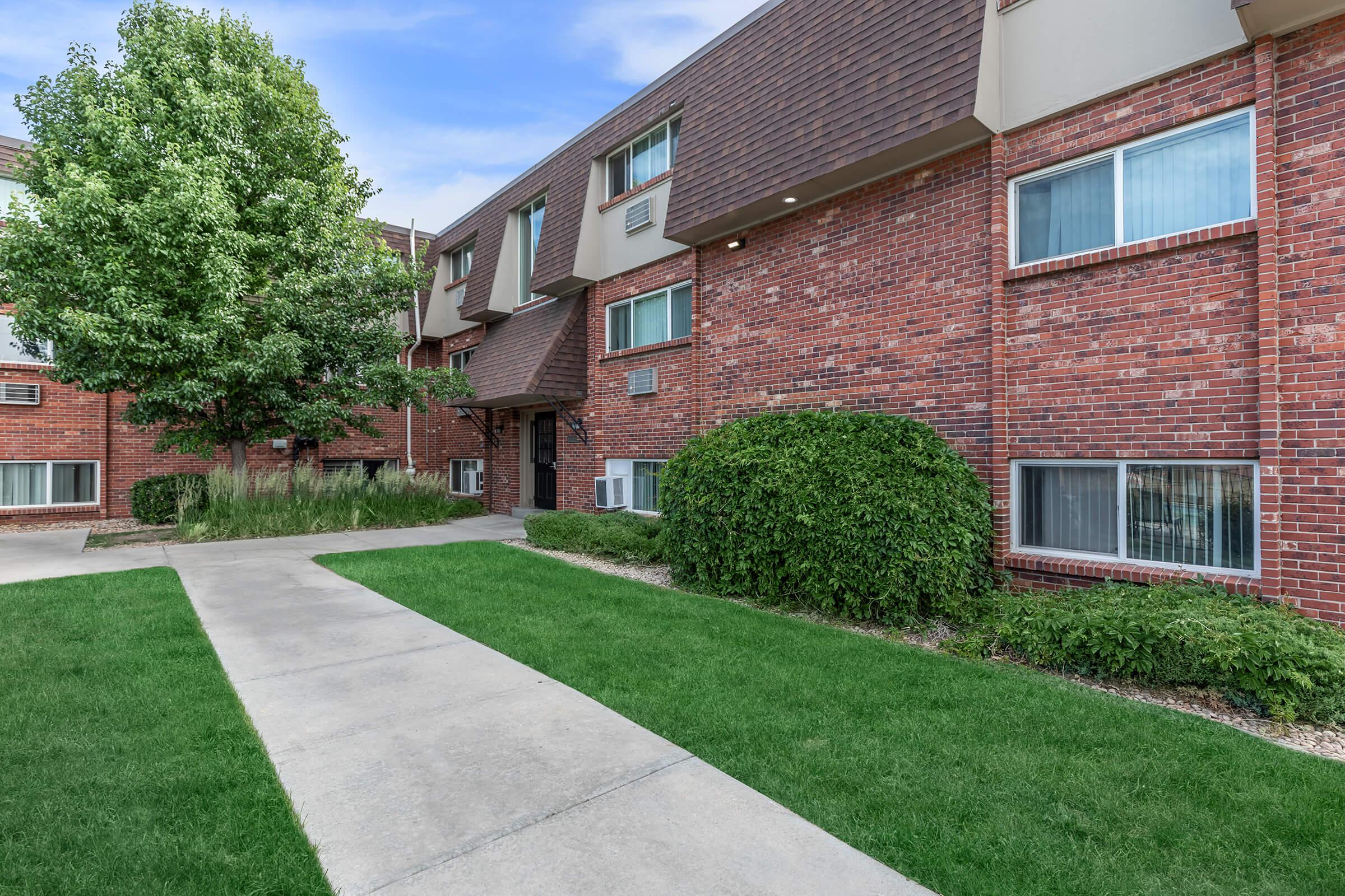 a house with a lawn in front of a brick building