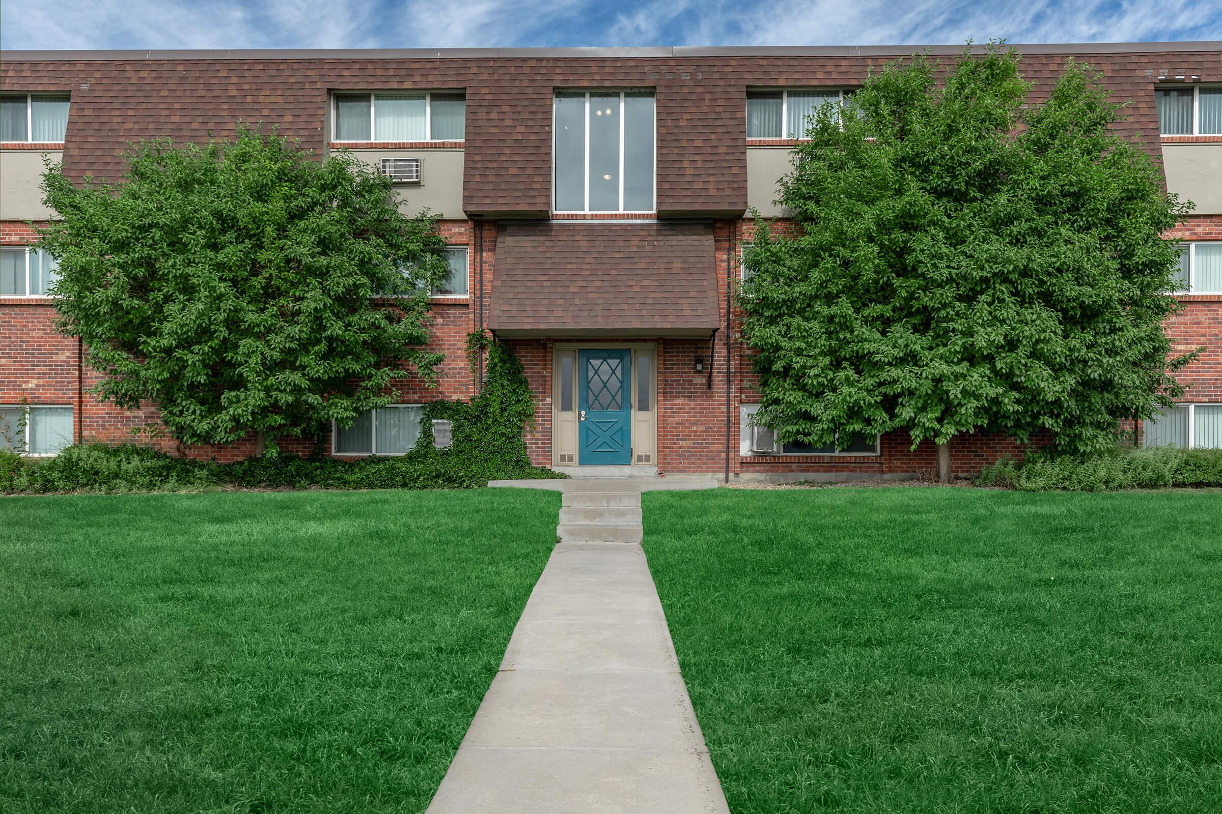 a large brick building with green grass in front of a house