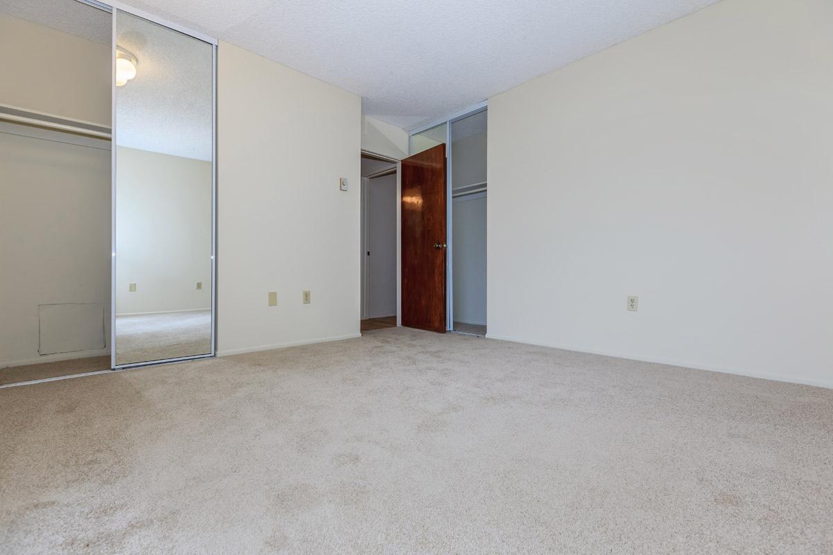 Vacant bedroom with sliding mirror glass closet doors