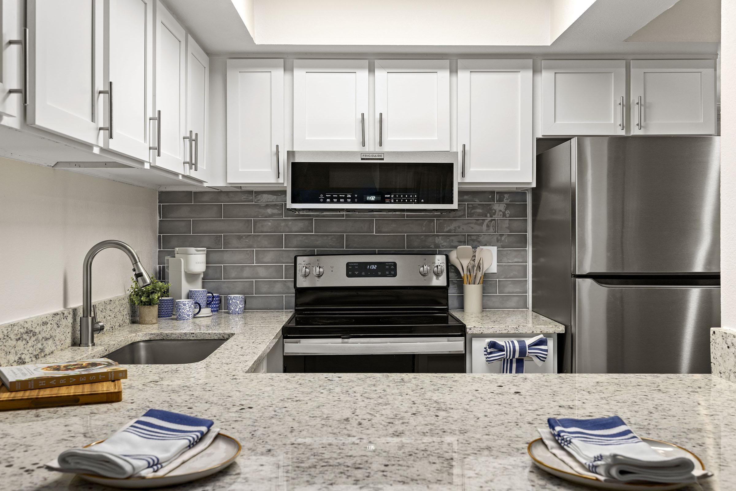 Model apartment kitchen with white cabinets.