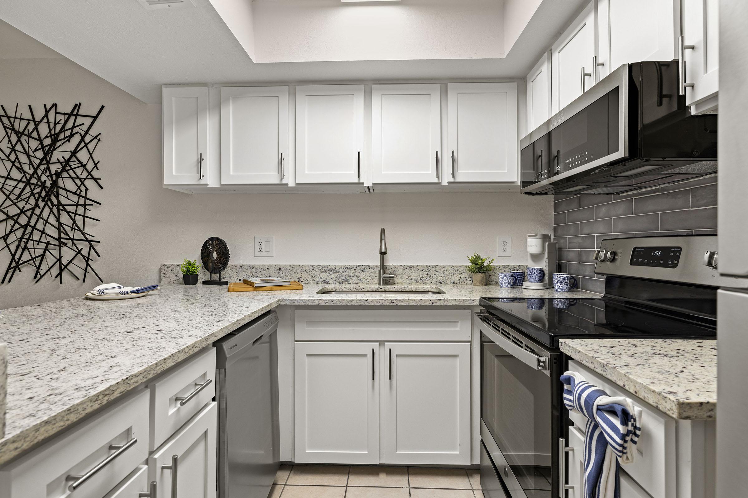 Model apartment kitchen with white cabinets.