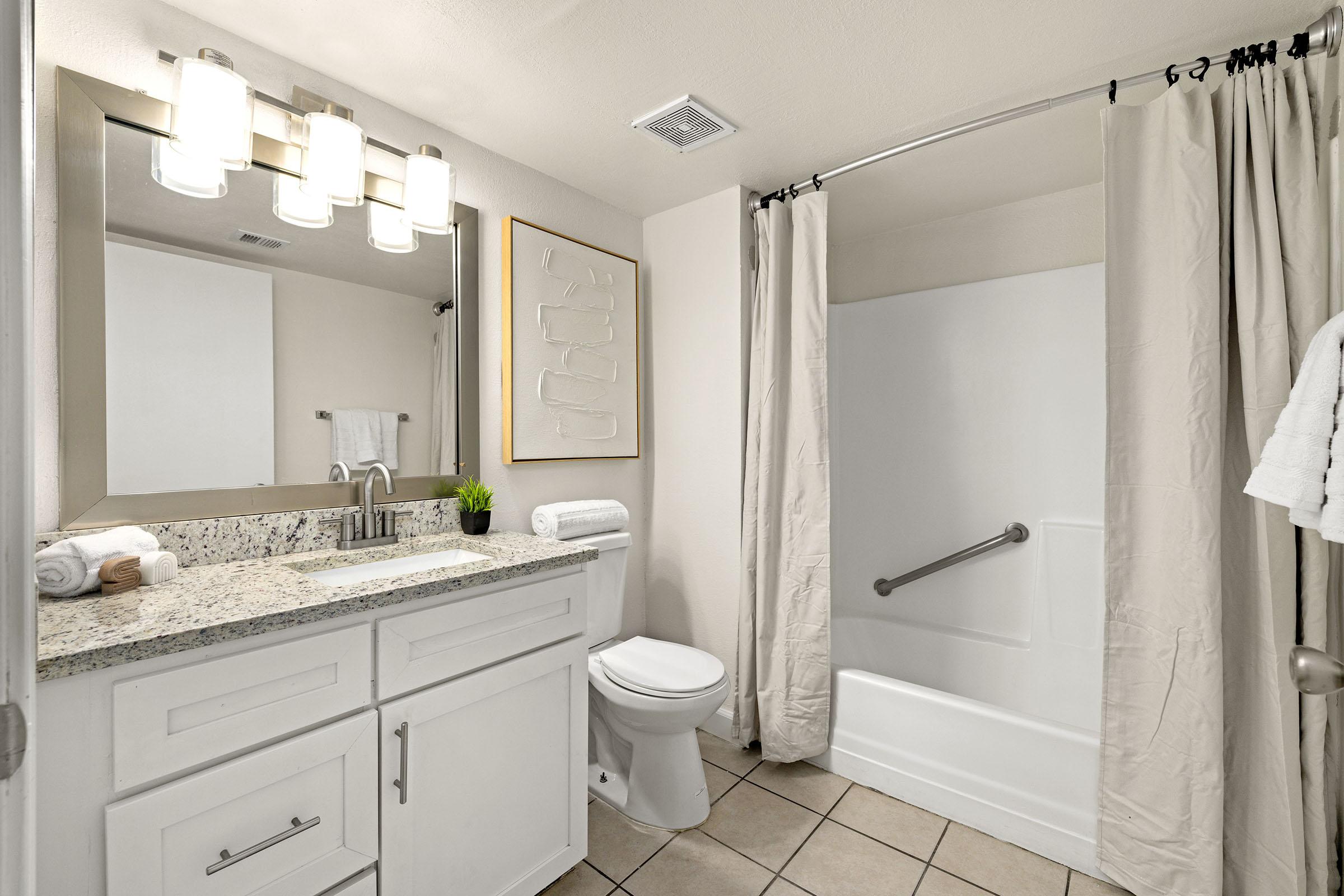 Model bathroom with tub, vanity and mirror.