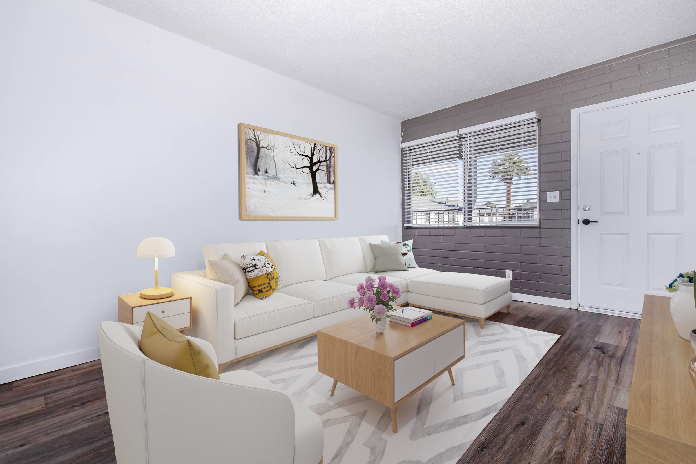 A modern living room featuring a white sofa with colorful cushions, a wooden coffee table, and a floor lamp. A wall-mounted artwork depicts a snowy landscape. Large windows with blinds allow natural light, and a door is visible on the right. The floor has a light area rug, adding warmth to the space.