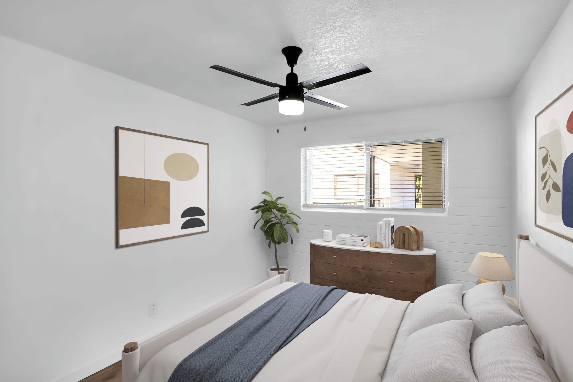 A bright, modern bedroom featuring a white color scheme. It includes a bed with white linens and a blue throw, a wooden dresser with decor items, a large fan overhead, and a window with light filtering through. A plant adds a touch of greenery, and abstract artwork hangs on the wall.