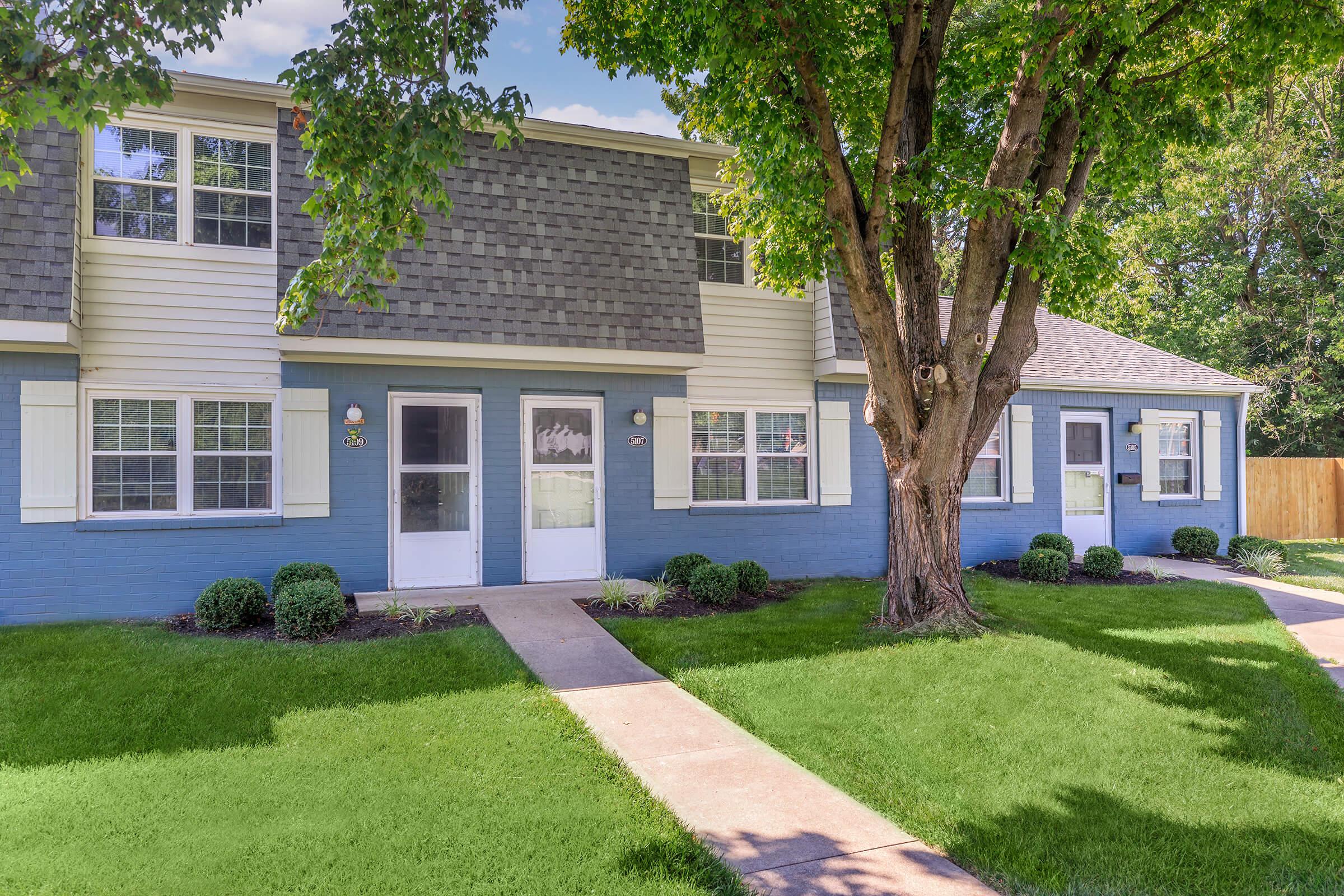 a house with a lawn in front of a brick building