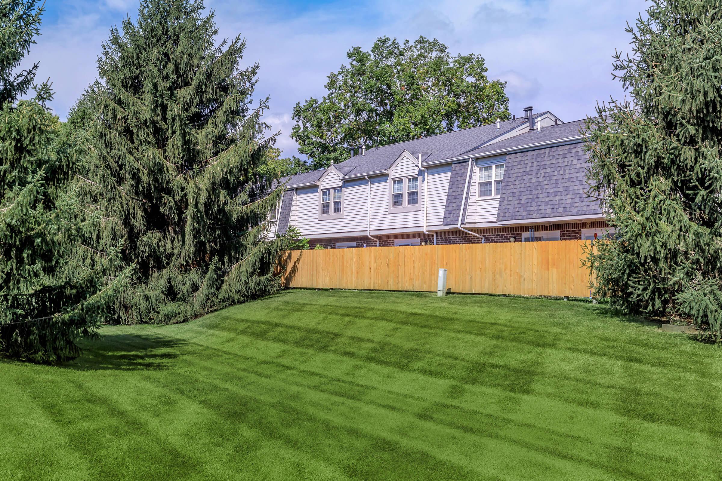 a building with a grassy field with trees in the background