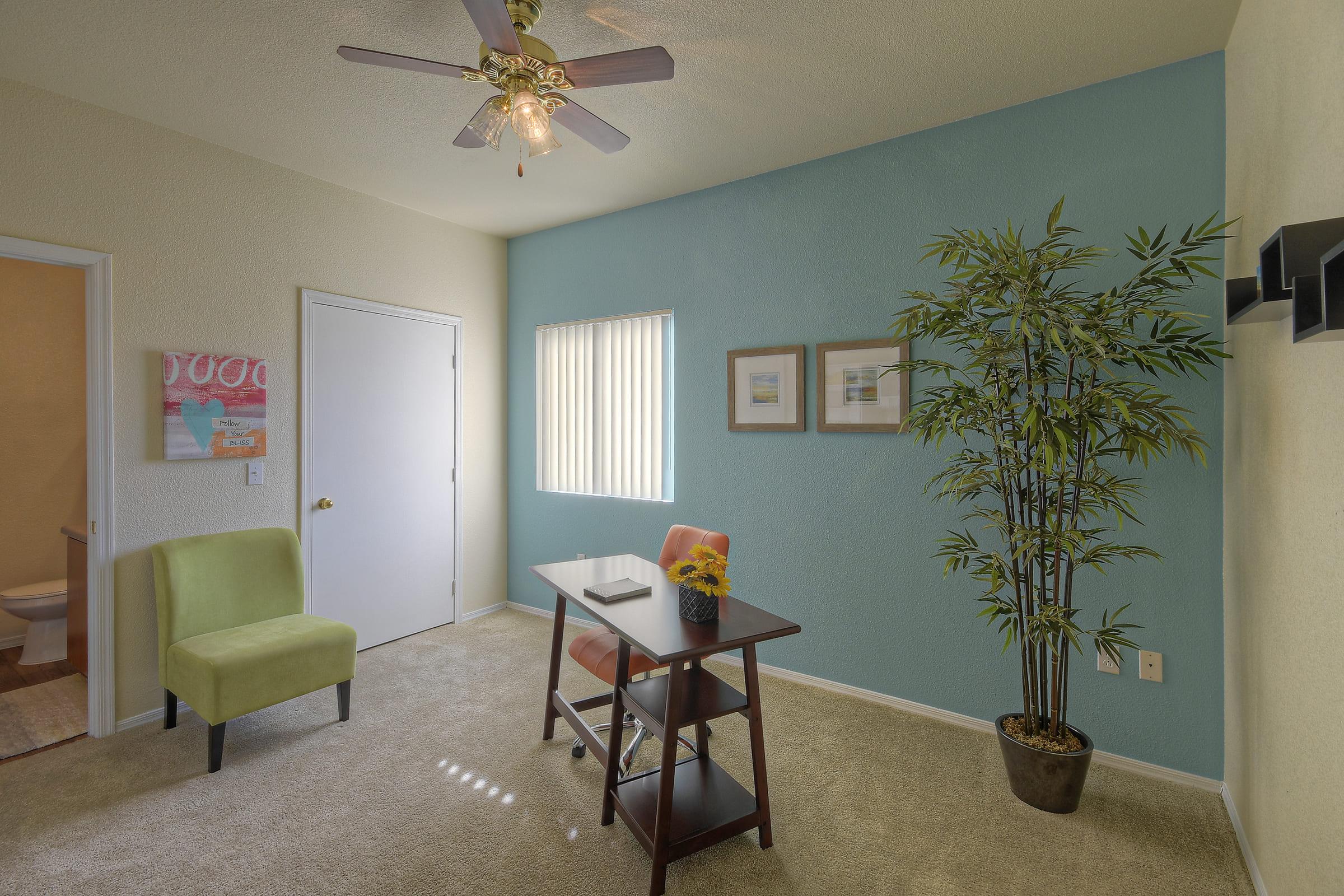A well-lit, tidy office space featuring a wooden desk with a notebook and sunflower.