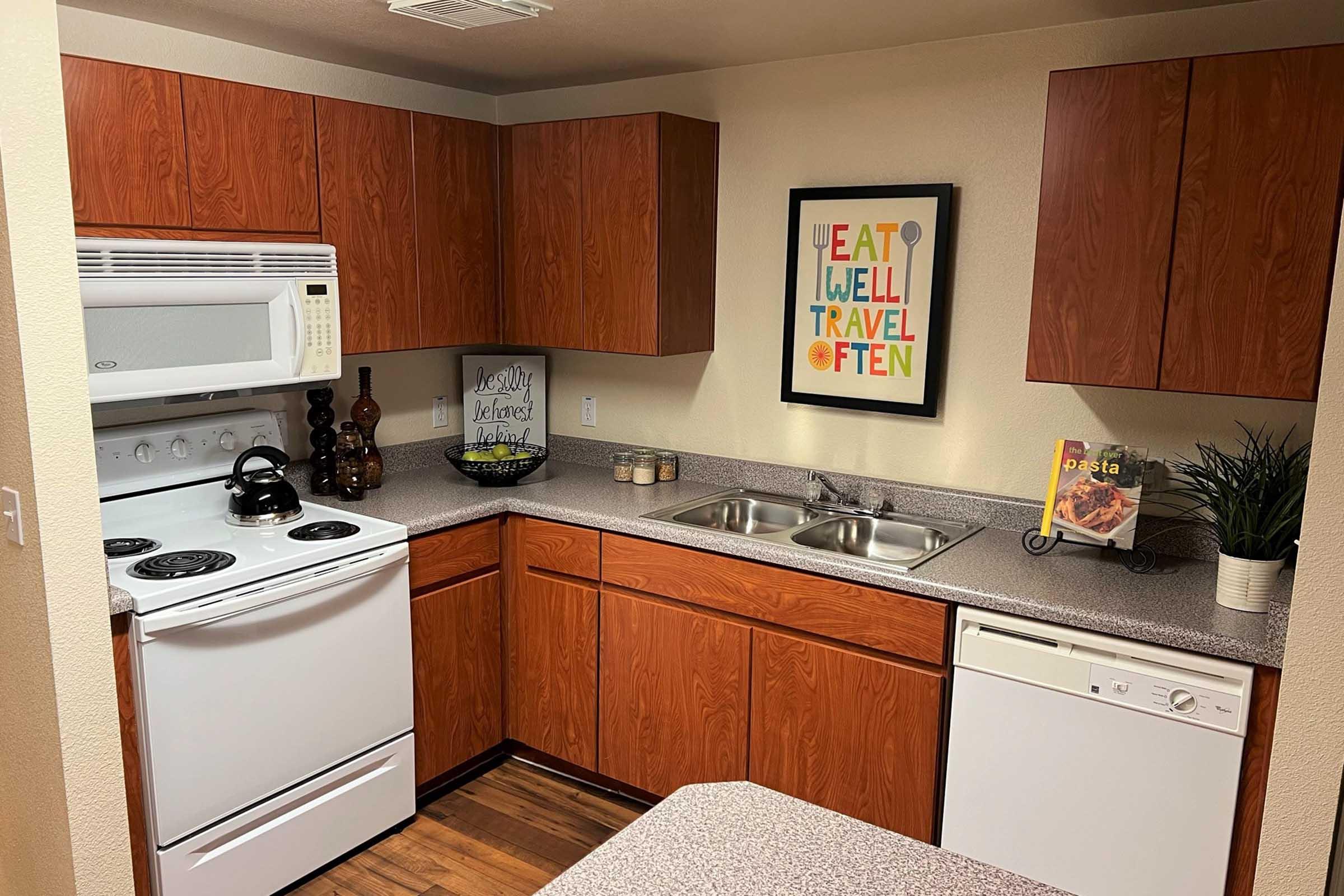  Modern kitchen featuring wooden cabinetry, a white stove and microwave, a sink with dual basins, and a dishwasher.