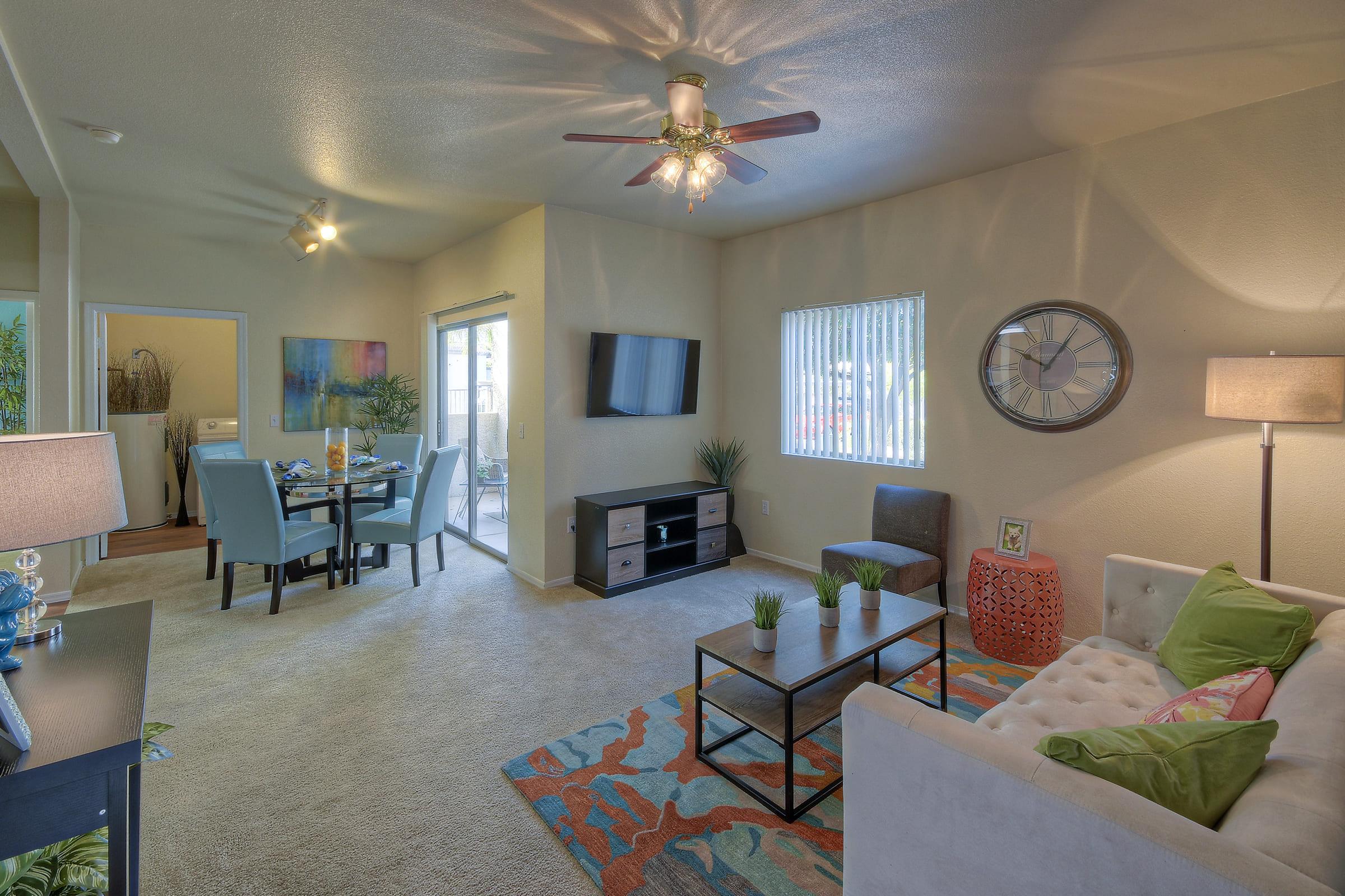 A modern living room featuring a beige sofa with colorful pillows, a coffee table, and a patterned area rug.