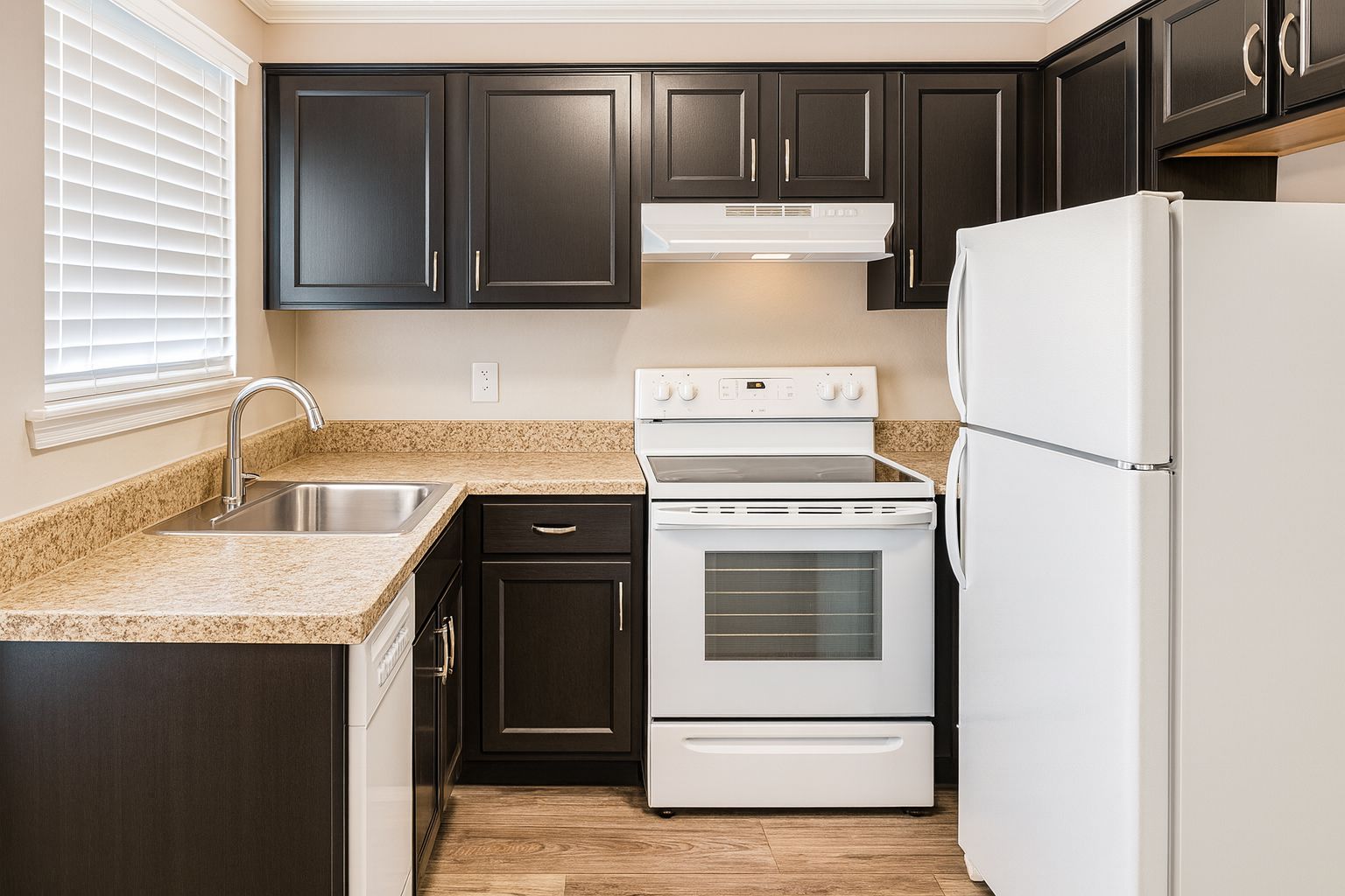 Modern kitchen featuring dark wood cabinetry, a white refrigerator, a white stove with an oven, and a stainless steel sink. The countertops are light-colored granite, and there is a window with blinds allowing natural light into the space. The floor is a light wood finish.