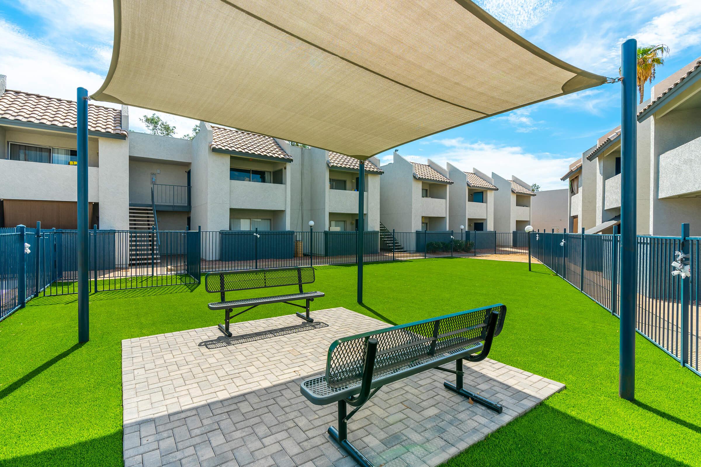 The enclosed dog park area with seating an an awning at Rise Thunderbird. 