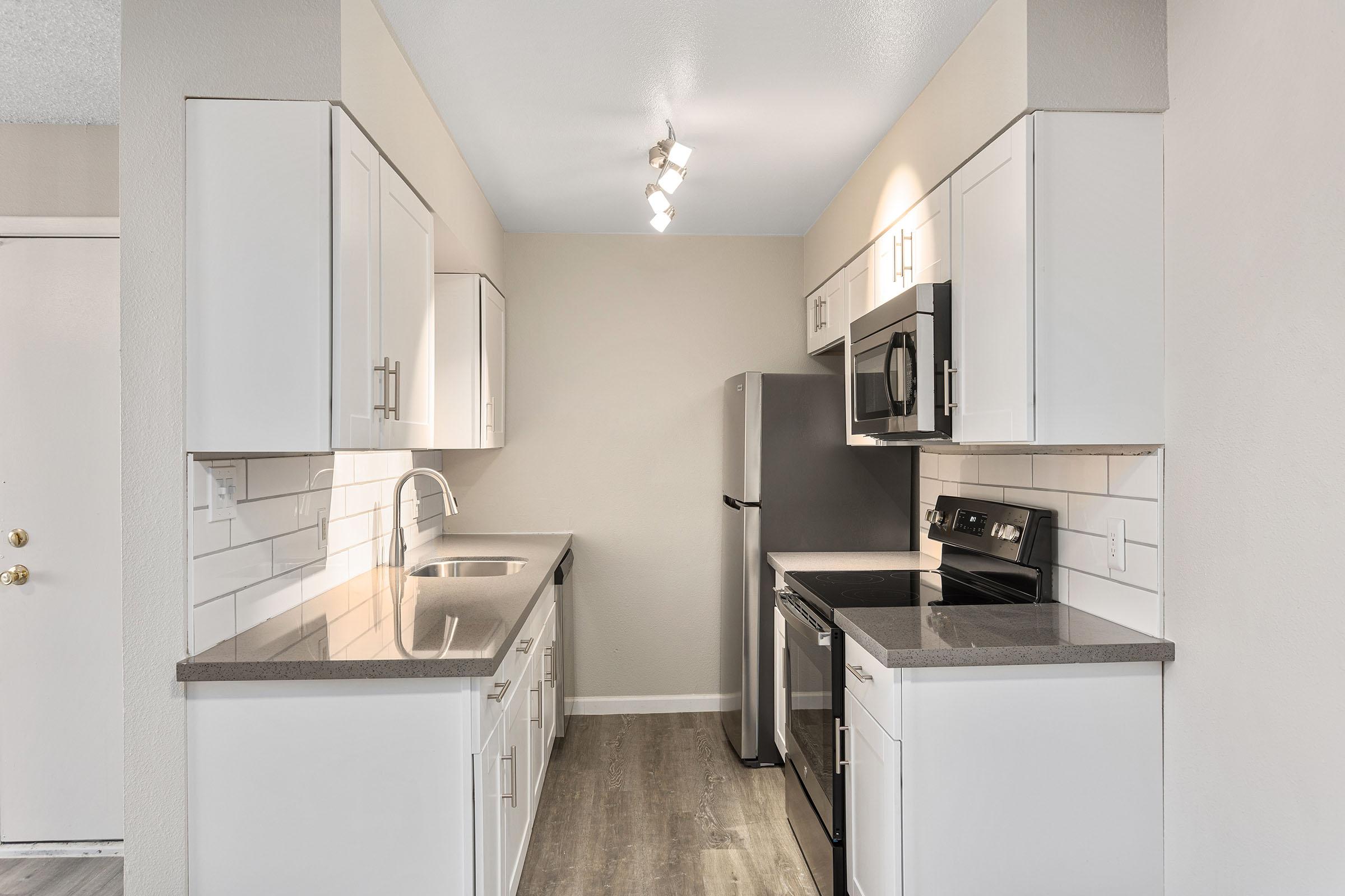 A remodeled galley kitchen with stainless steel appliances and white shaker cabinets at Rise Thunder