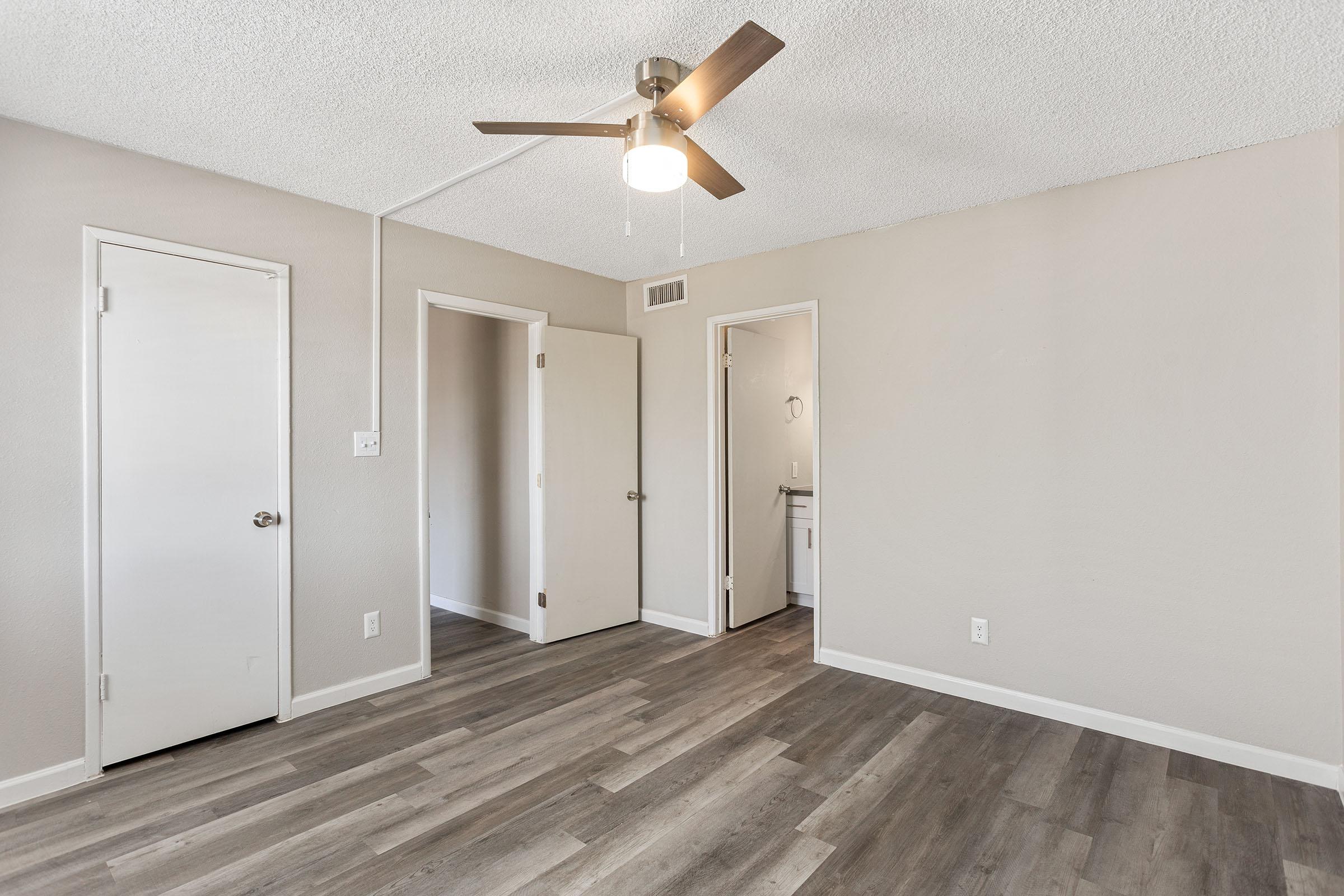 A bedroom with wood-style flooring and an en-suite bathroom at Rise Thunderbird. 