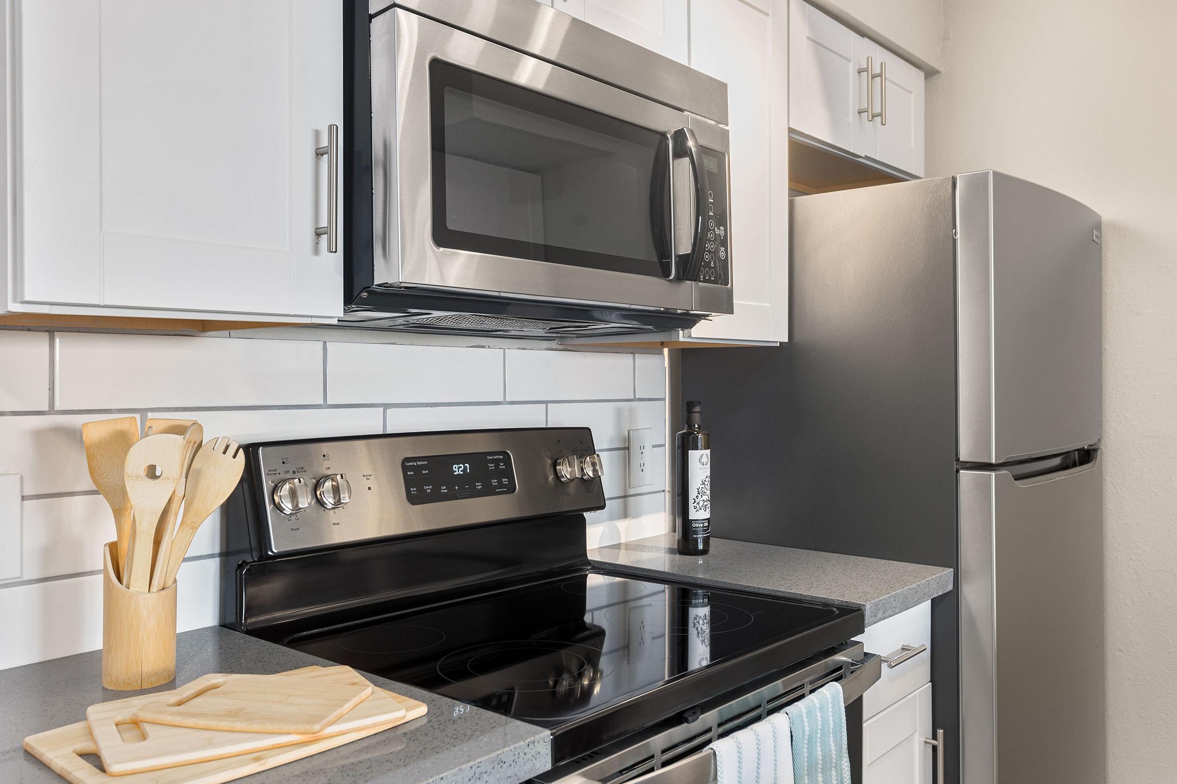 A kitchen with stainless steel appliances and white shaker cabinets at Rise Thunderbird. 