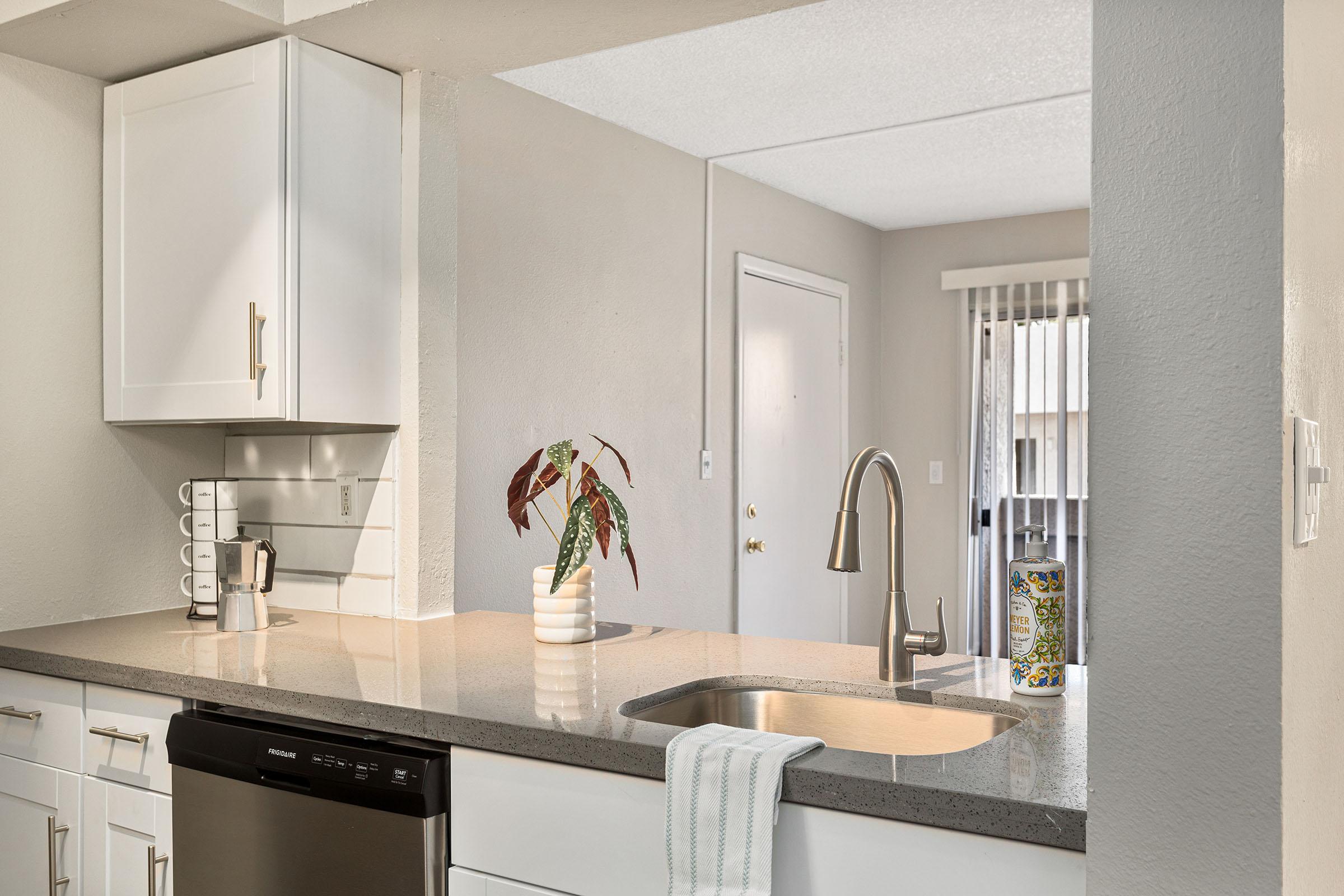 A kitchen with white shaker cabinets and stainless steel appliances at Rise Thunderbird. 