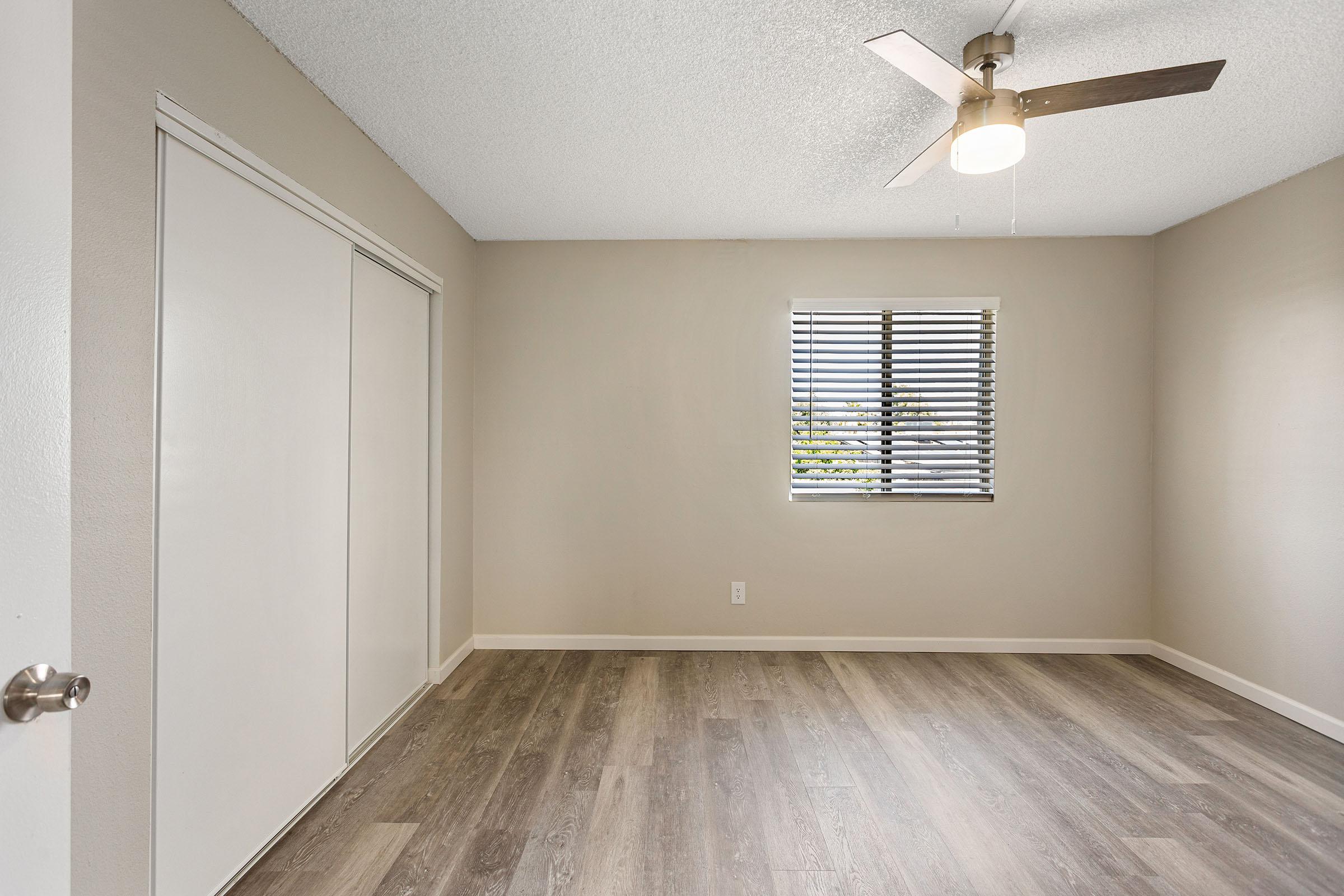 A bedroom with wood-style flooring and a closet at Rise Thunderbird. 