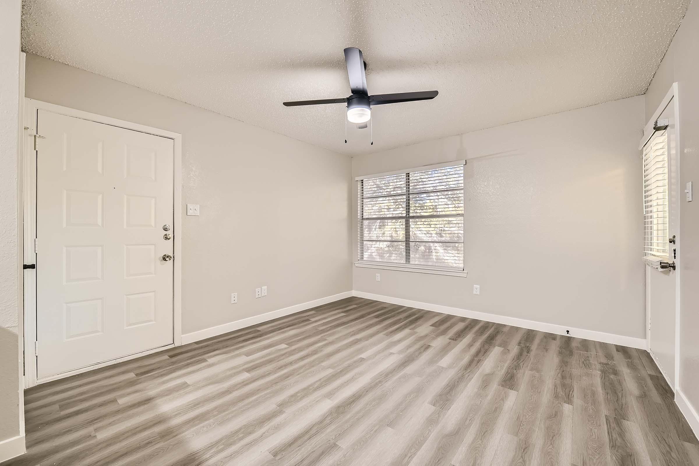 Empty apartment bedroom with wood flooring and ceiling fan at Rise Bedford Lake in Bedford, TX