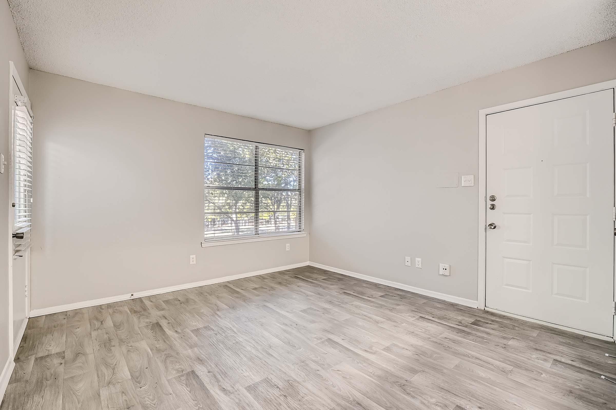 Empty apartment living room with wood flooring and window at Rise Bedford Lake in Bedford, TX