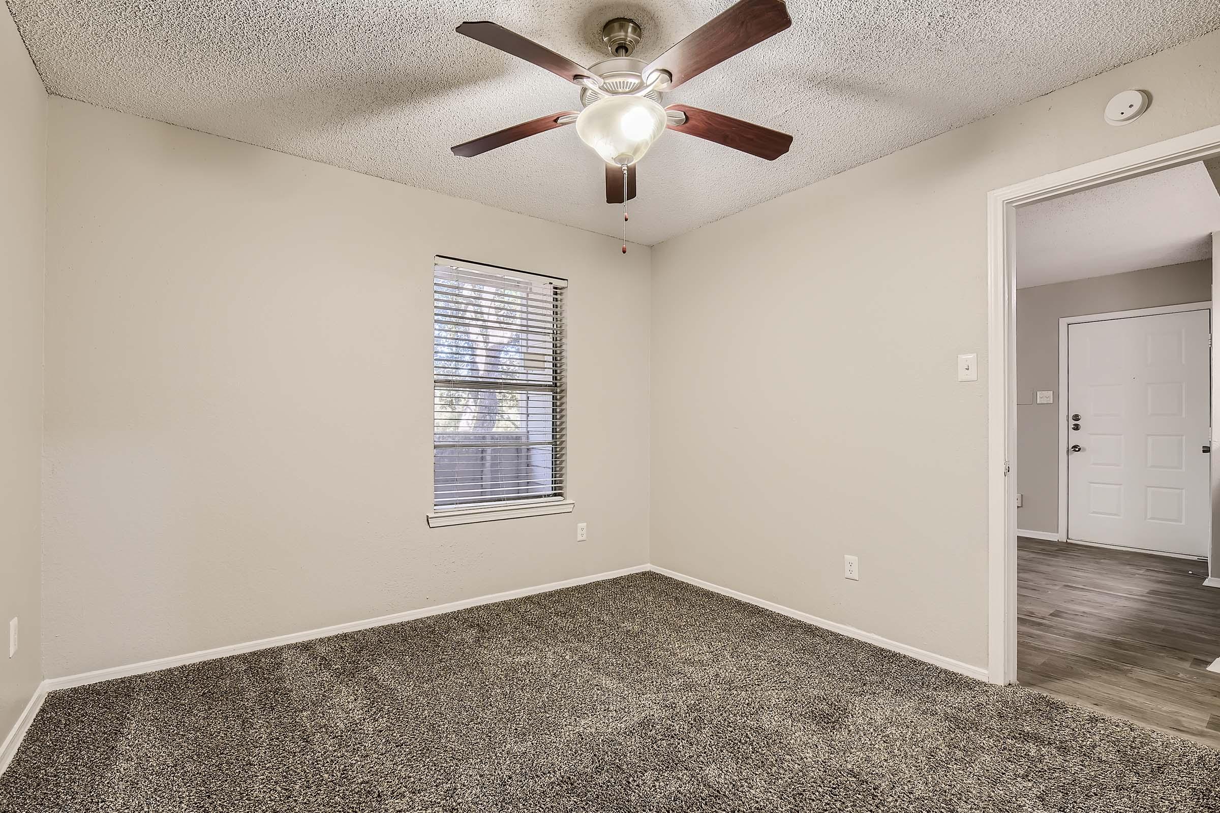 Empty carpeted apartment bedroom with ceiling fan at Rise Bedford Lake in Bedford, TX