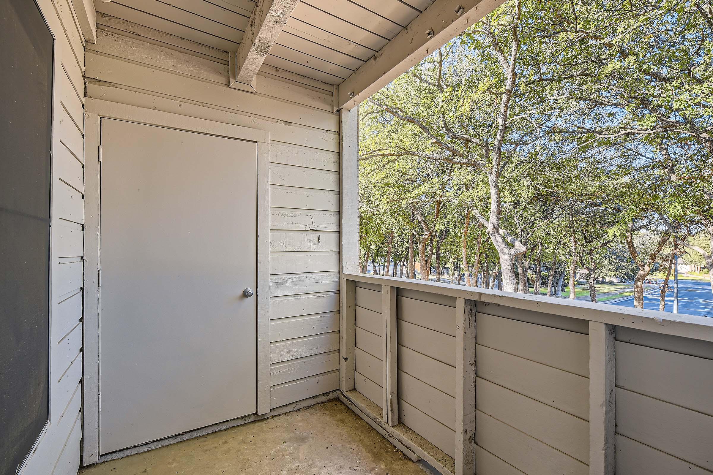 Outdoor apartment covered balcony with a view of the trees in Bedford, TX