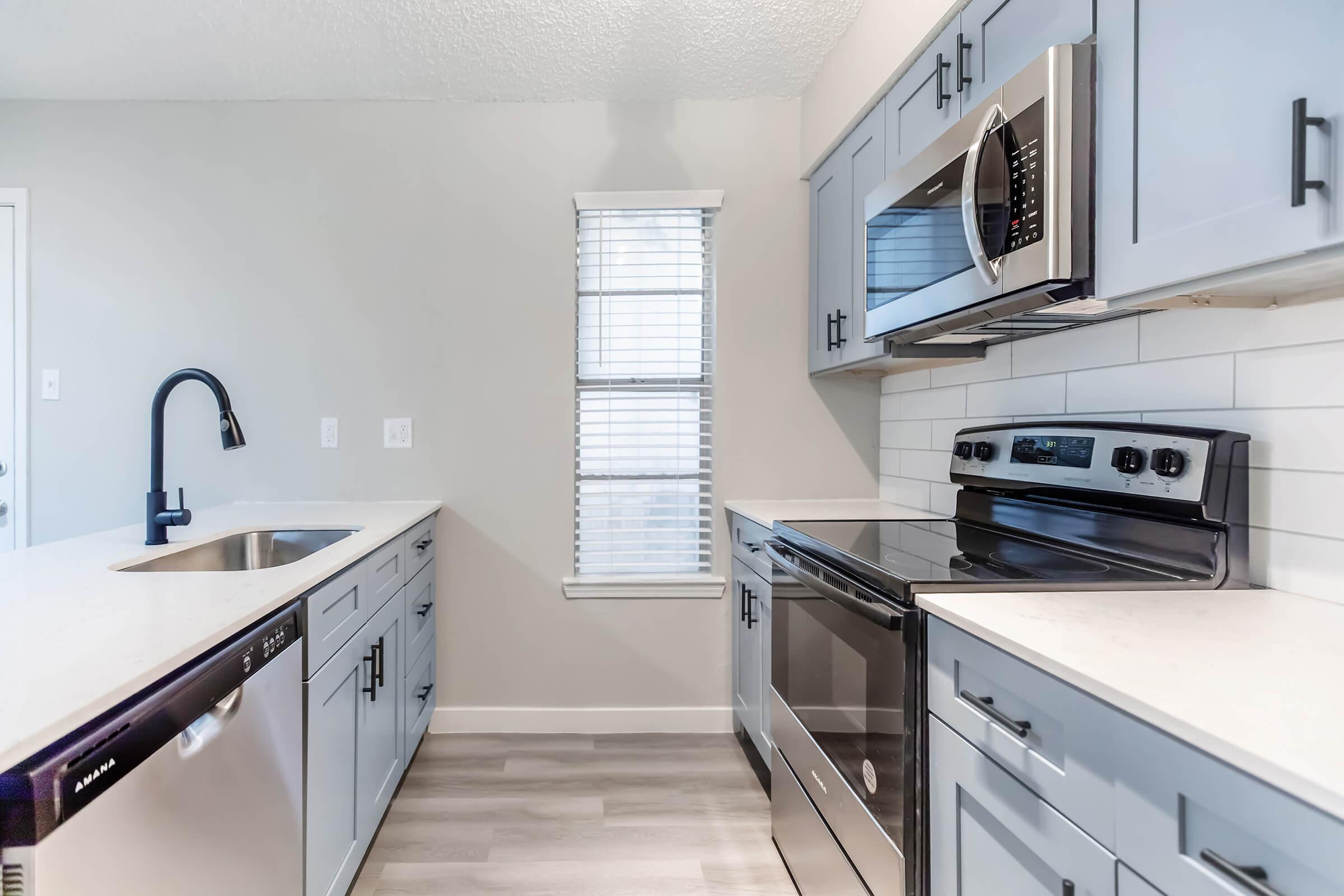 Apartment kitchen with stove, microwave, sink, dishwasher, and washer/dryer in Bedford, TX