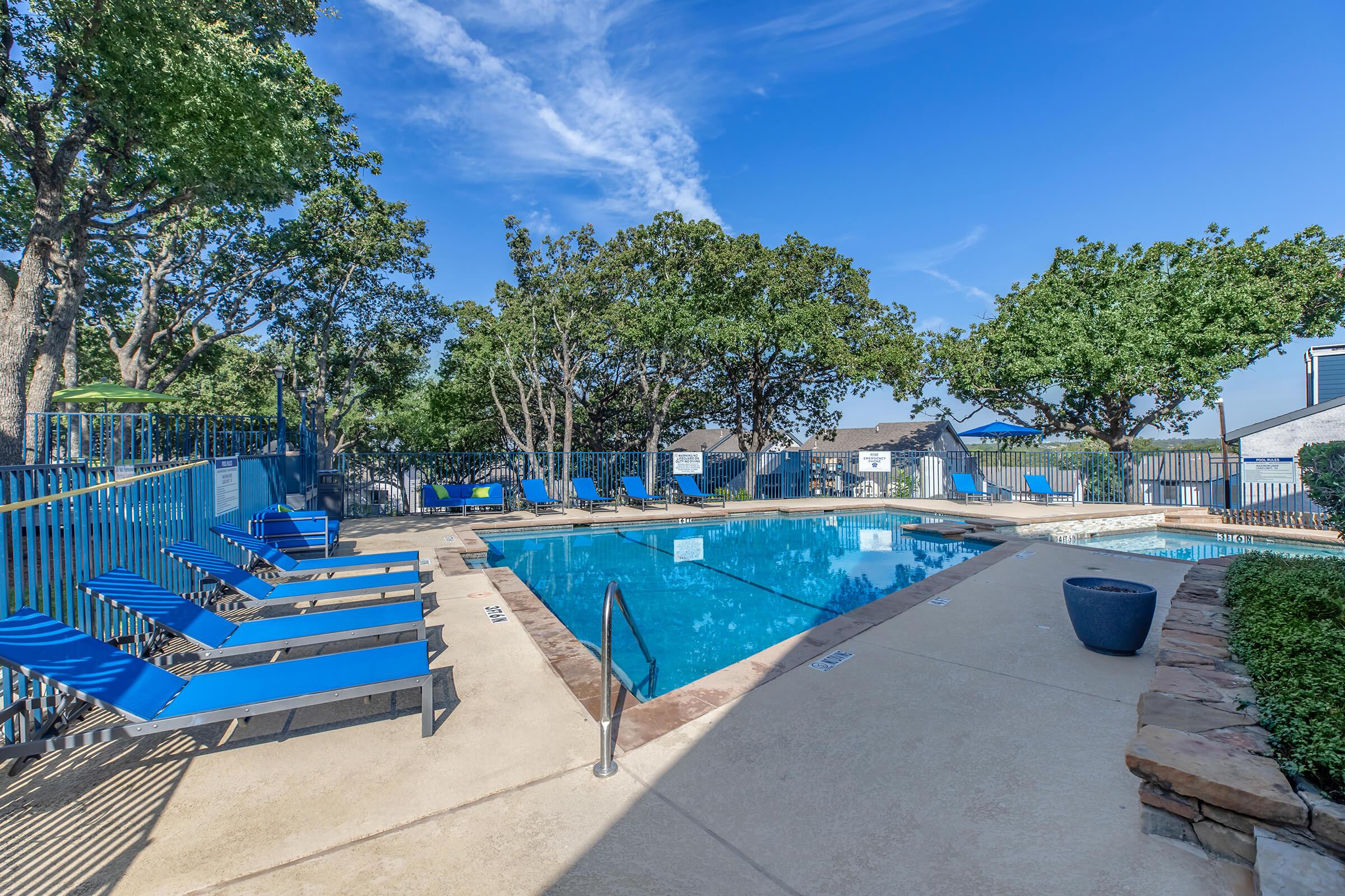 Bedford Lake apartment outdoor swimming pool with blue lounge chairs in Bedford, TX	