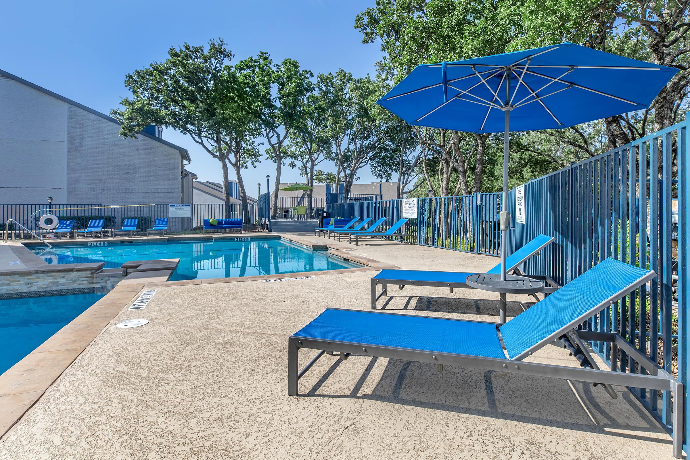 Blue umbrella and lounge chairs by the outdoor pool at Rise Bedford Lake