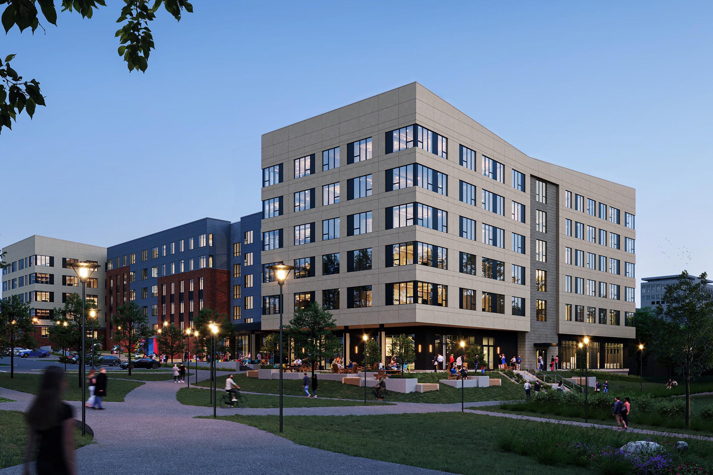 Modern multi-story buildings surrounded by lush green landscaping and pathways. People are gathered outside, enjoying the outdoor spaces and seating areas. The scene is set during twilight, with warm lights illuminating the building's facades and pathways.