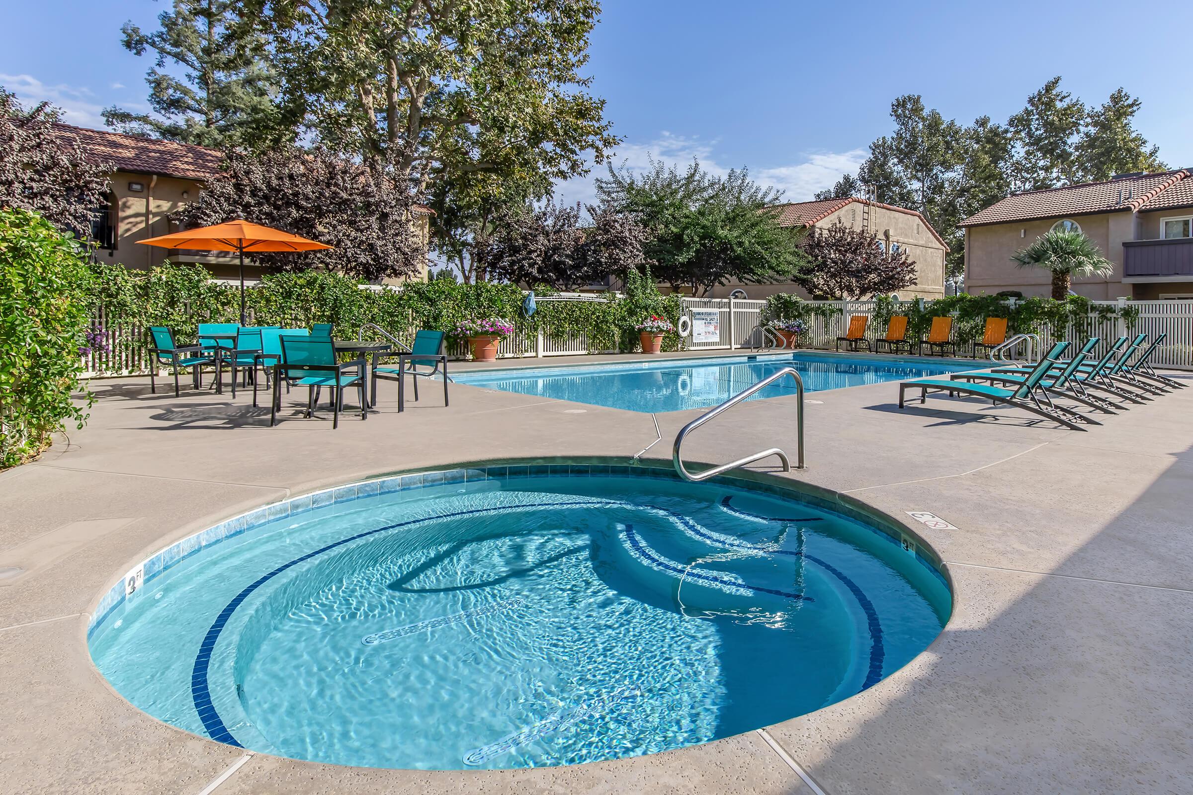 3-Bedroom Apartments in Visalia, CA - Oak View - Swimming Pool with Lounge Chairs and a Spa Surrounded by Lush Greenery